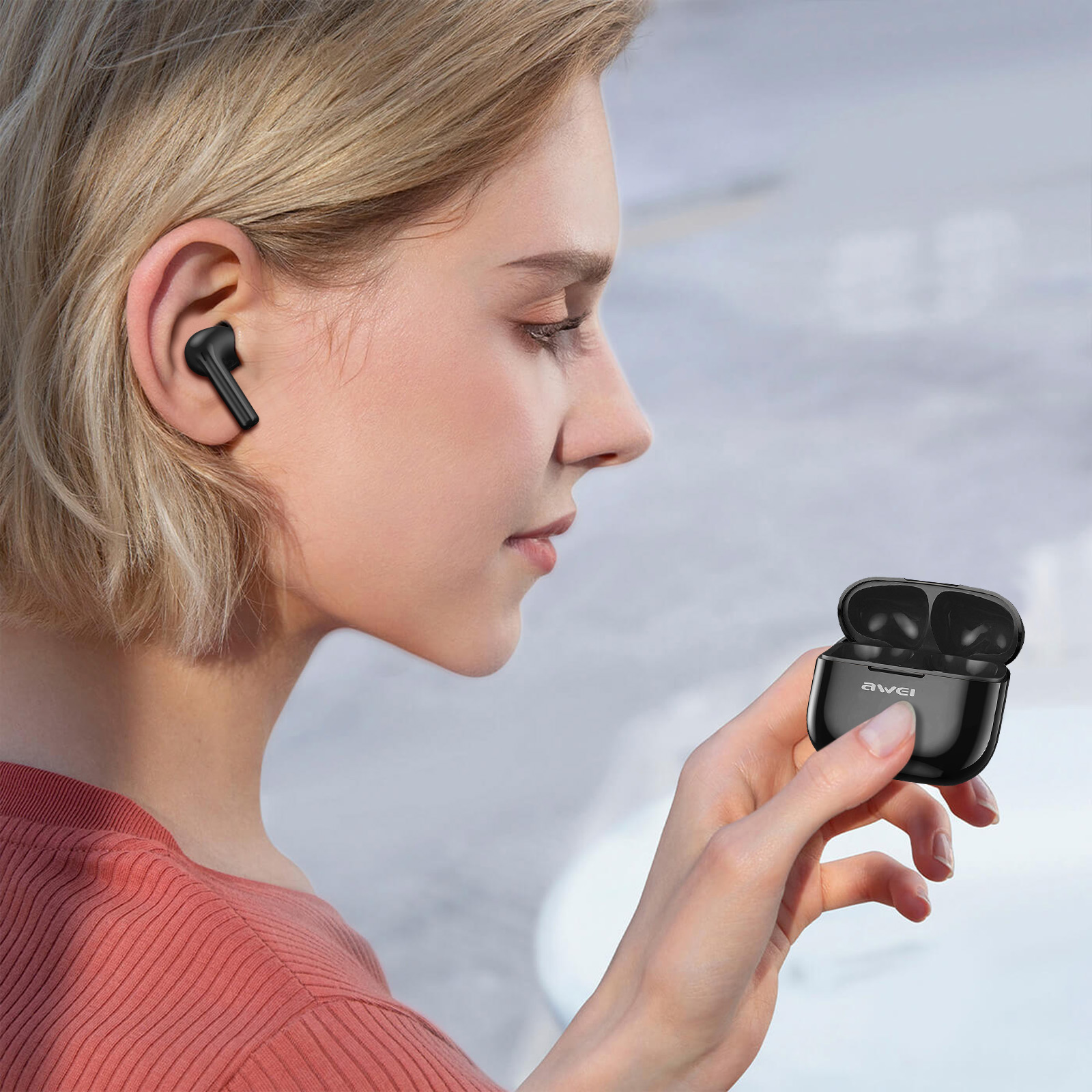 Una donna con auricolari neri nell'orecchio. Tiene in mano una custodia di ricarica.