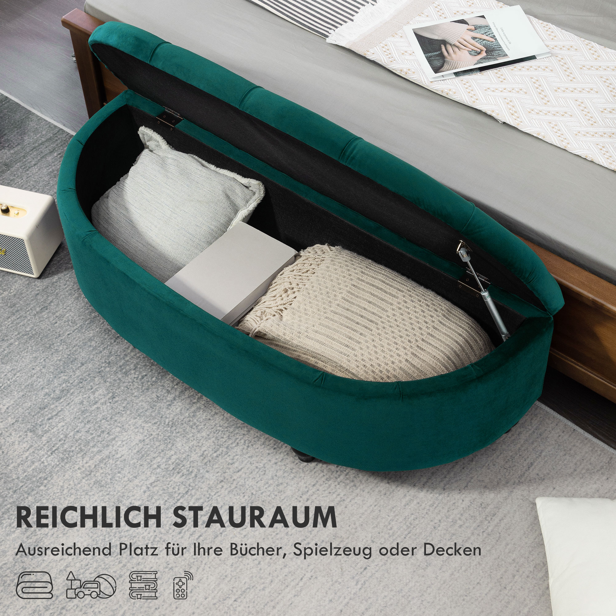 Grünes Ottoman mit offenem Stauraum, gefüllt mit Kissen und Decken, auf grauem Teppich.
