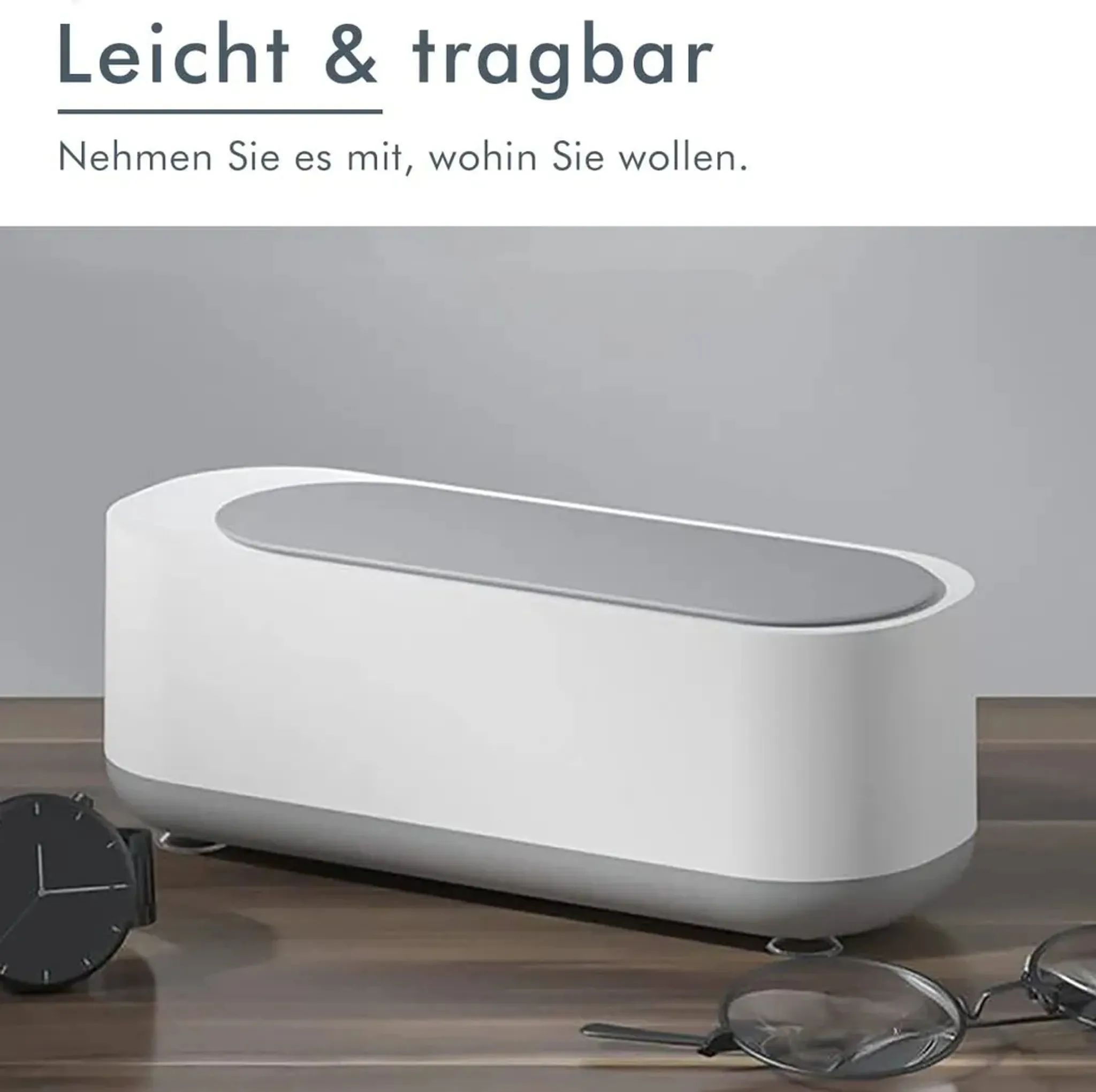 Weißer und grauer Ultraschallreiniger mit Uhr und Brille, auf Holzoberfläche.