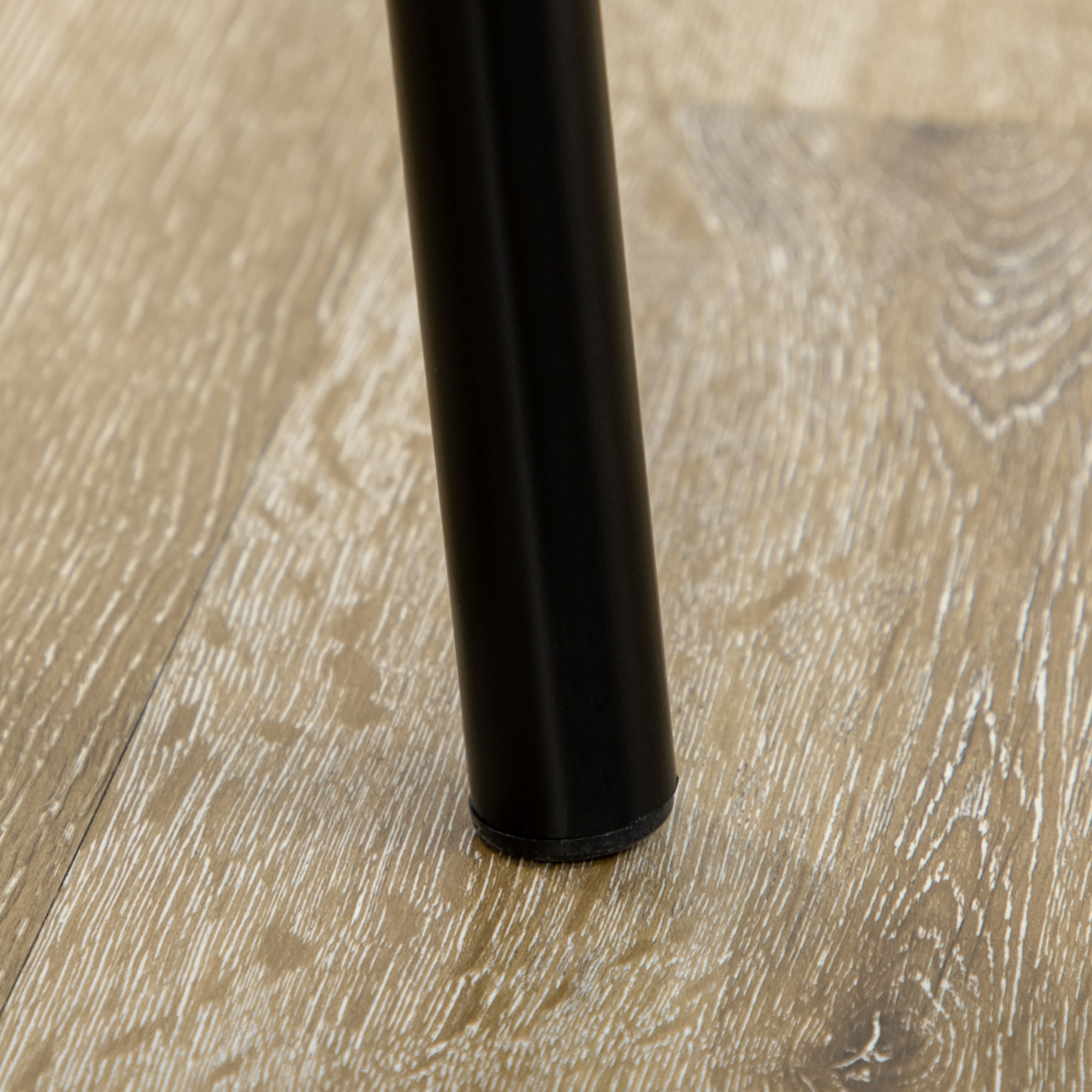Ein schwarzes Stuhlbein auf Holzboden, das den Sockel und die Befestigung zeigt.