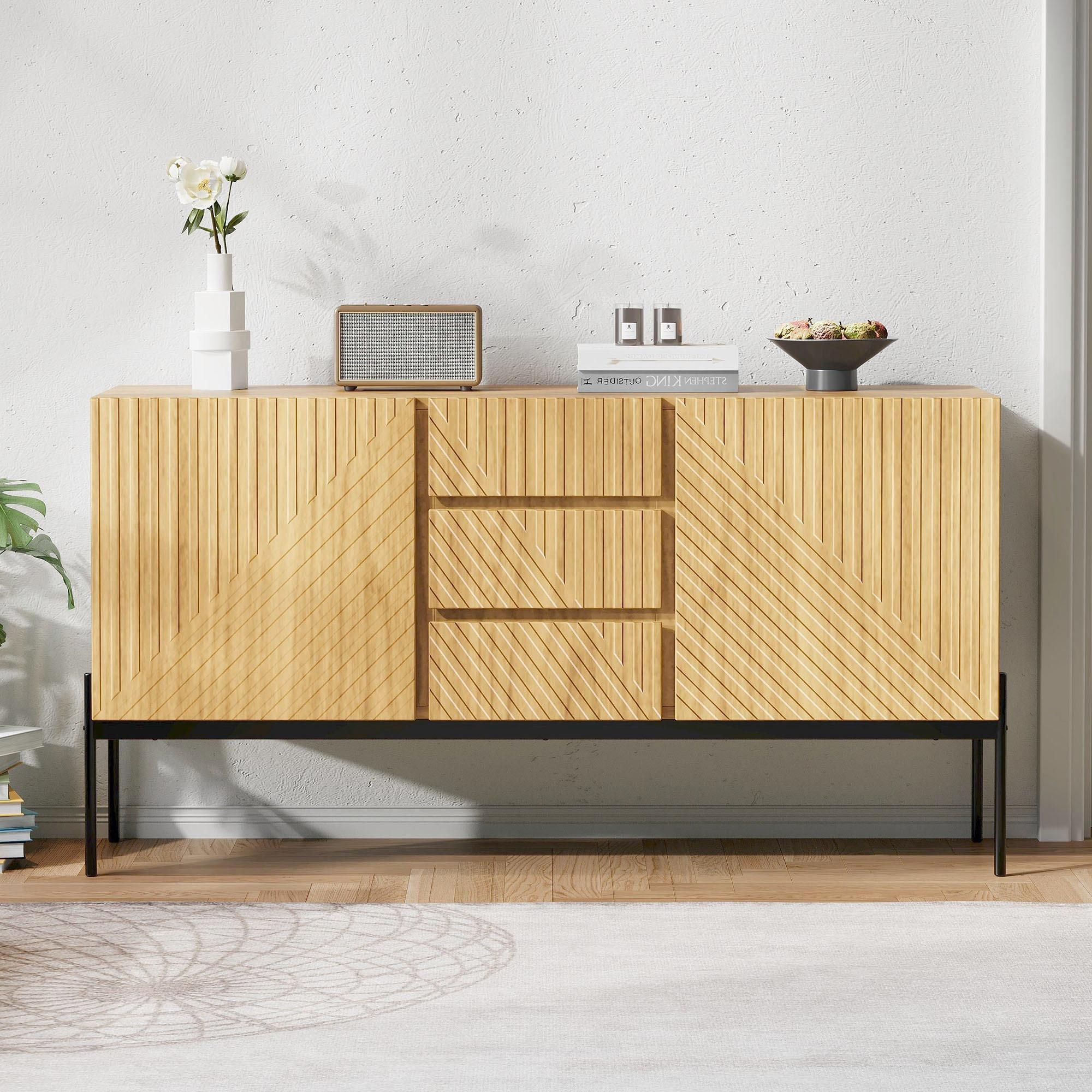 Holzschrank mit drei Schubladen. Schwarzer Sockel mit strukturierter Holzfront. Weiße Wand im Hintergrund.