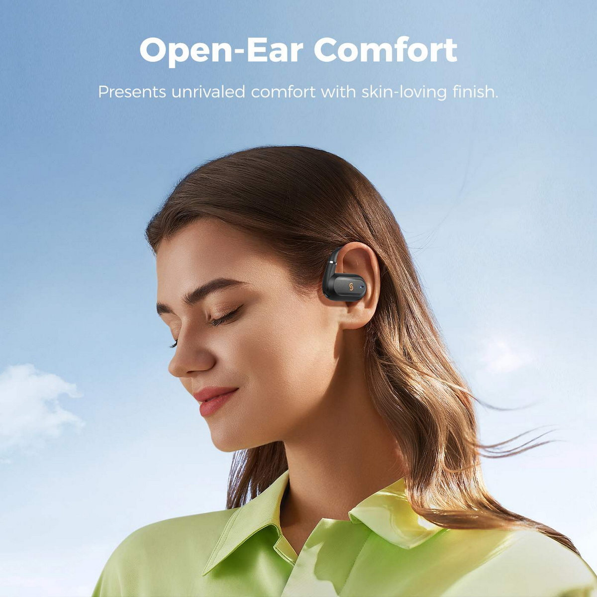 Donna con auricolare, indossa una camicia verde. Testo: Comfort Open-Ear. Finitura delicata sulla pelle.