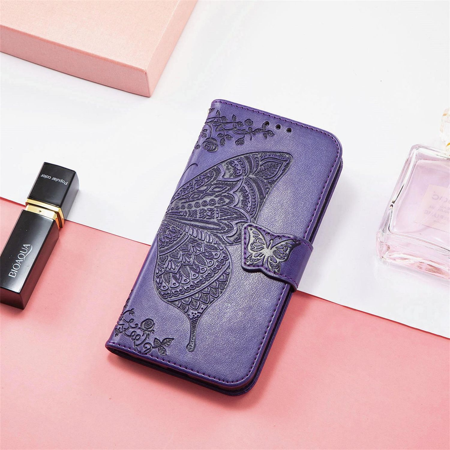 Funda de teléfono de cuero púrpura con diseño de mariposa, un frasco de perfume y un lápiz labial.