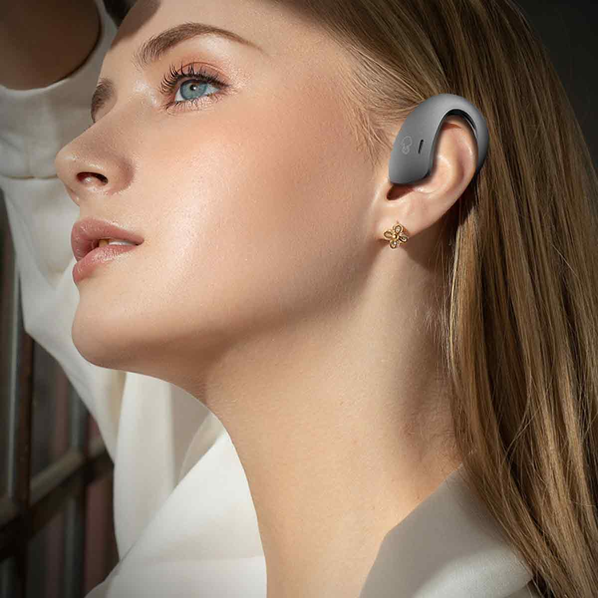 Frau mit grauem In-Ear-Hörgerät. Nahaufnahme ihres Gesichts und Ohres.