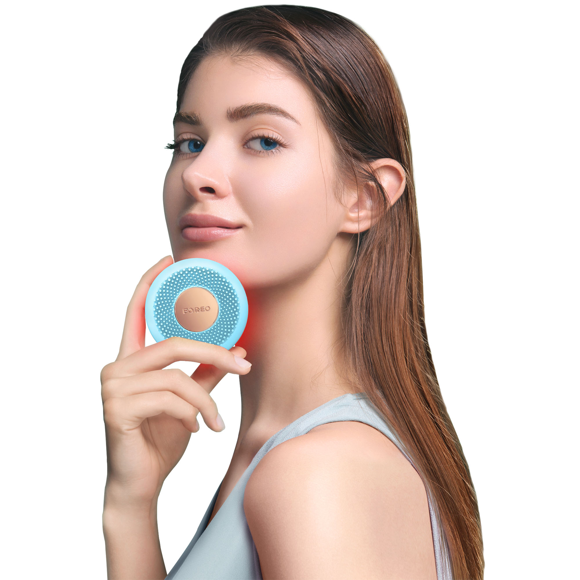 Una donna tiene un dispositivo blu sul viso. Il dispositivo è rotondo con un centro dorato.