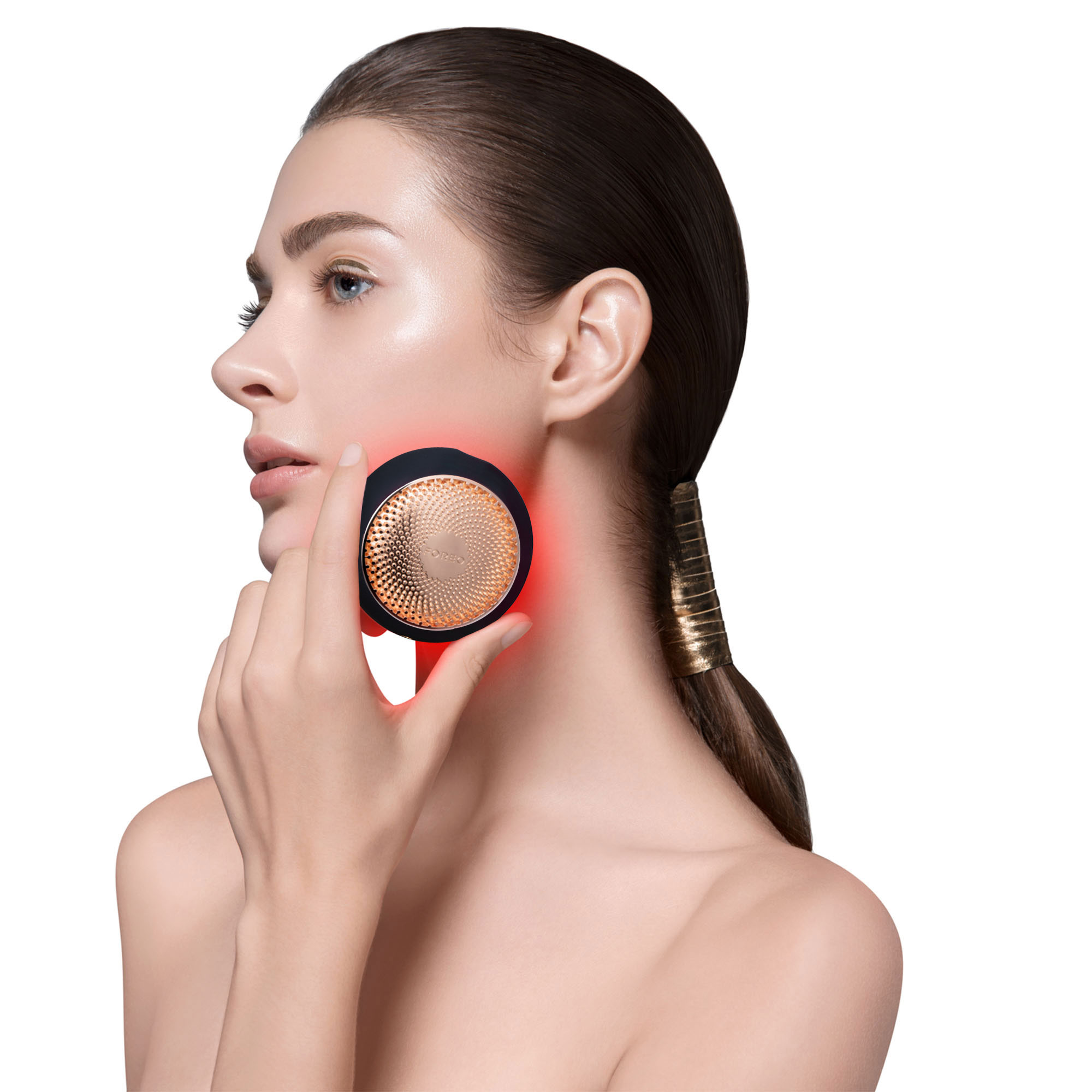 Mujer con un dispositivo de belleza en la cara, luz roja visible.
