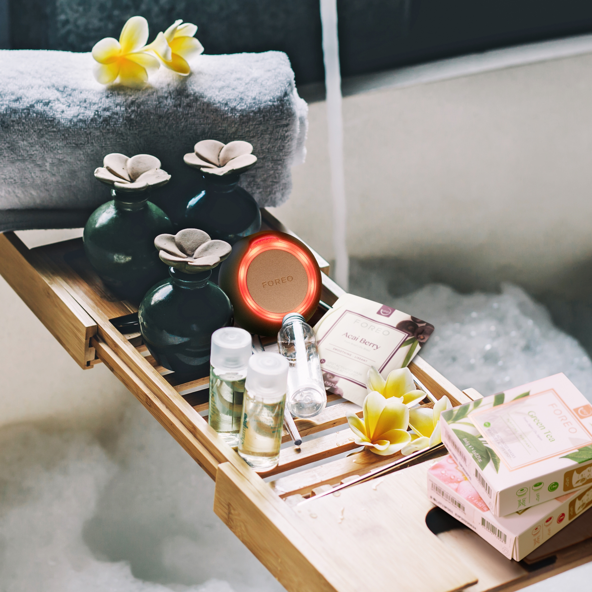 Escena de spa con bañera, velas y productos de belleza en una bandeja de madera.