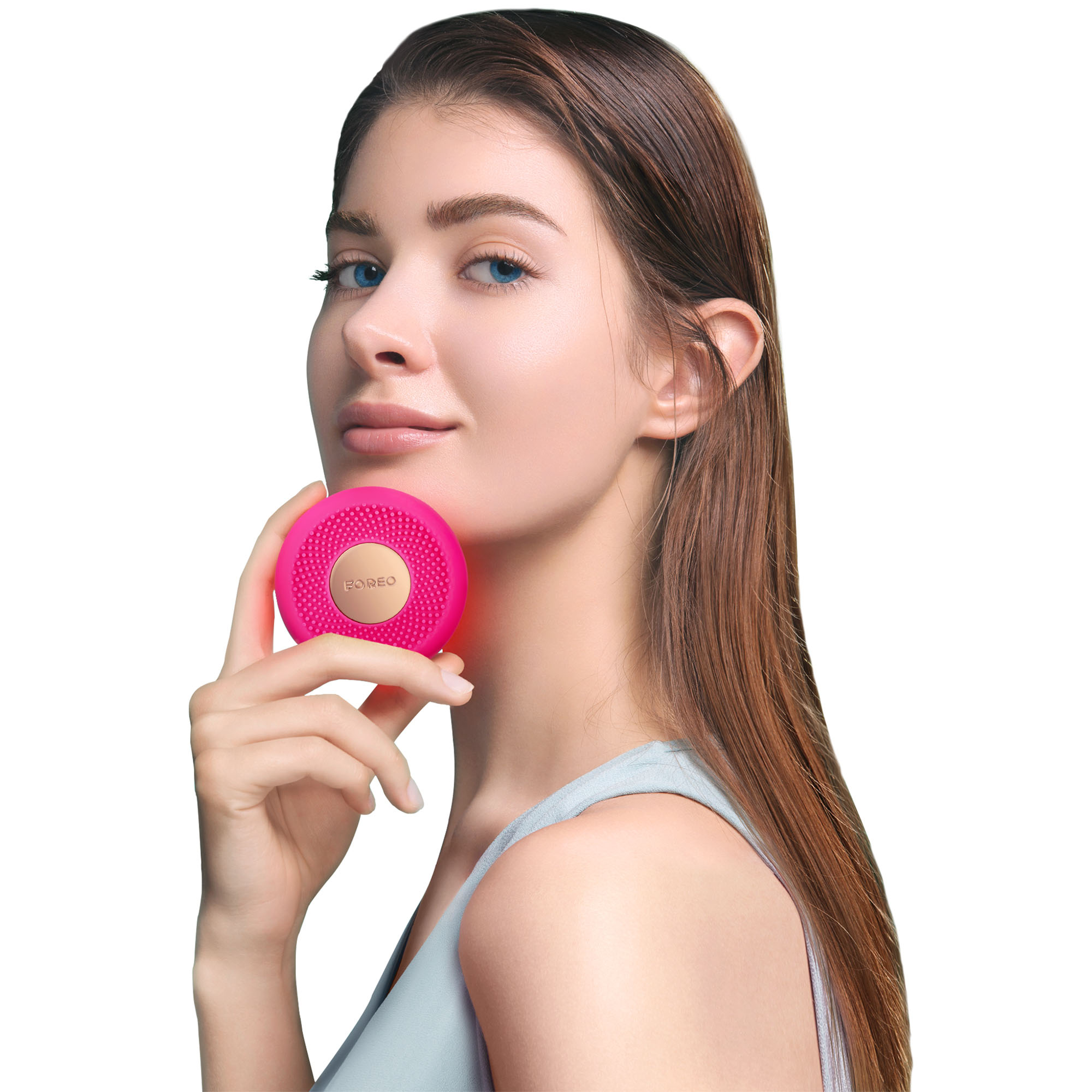 Donna con capelli lunghi tiene un dispositivo per la pulizia del viso rosa.