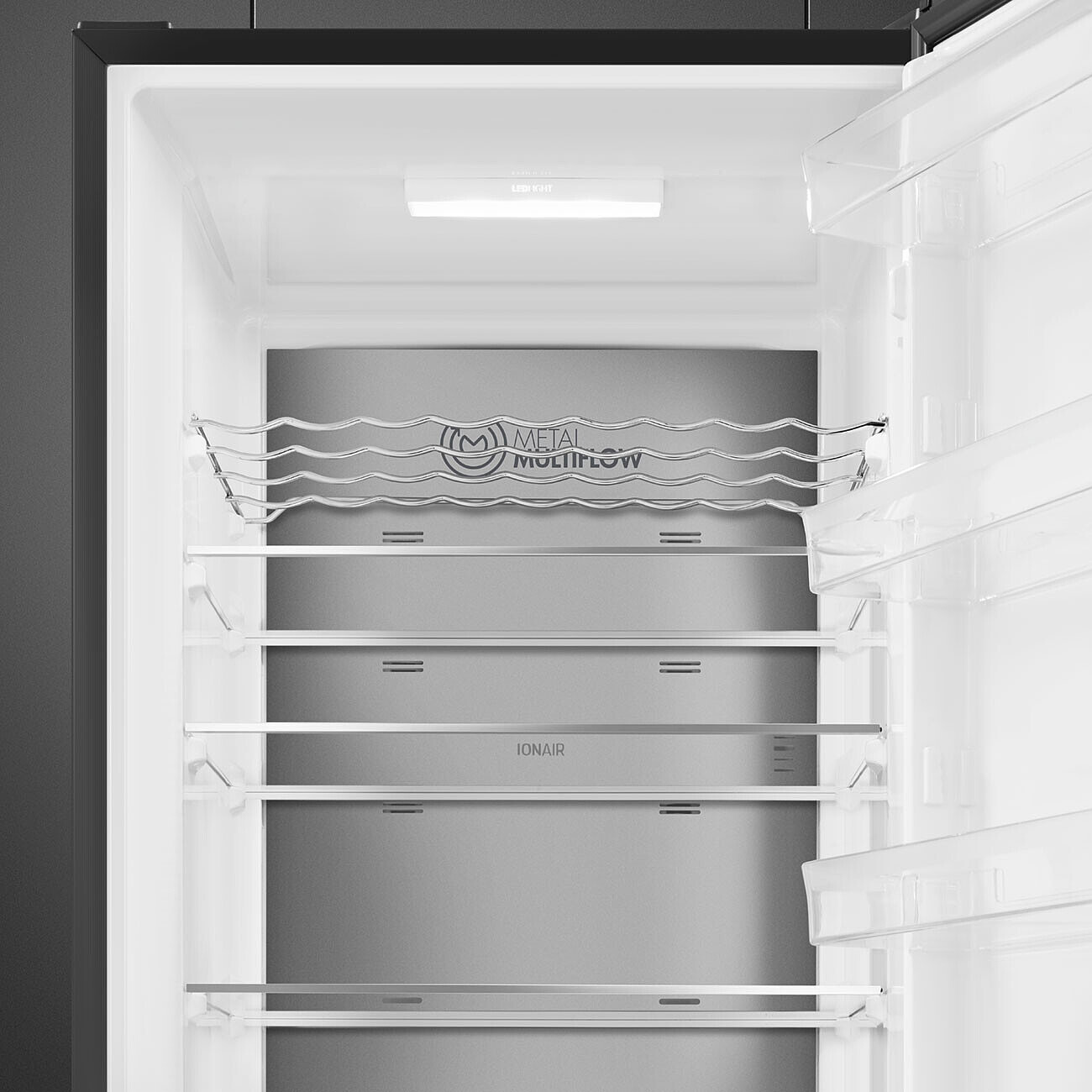 Wnętrze lodówki z półkami, metalowym systemem multi-flow i górnym oświetleniem.