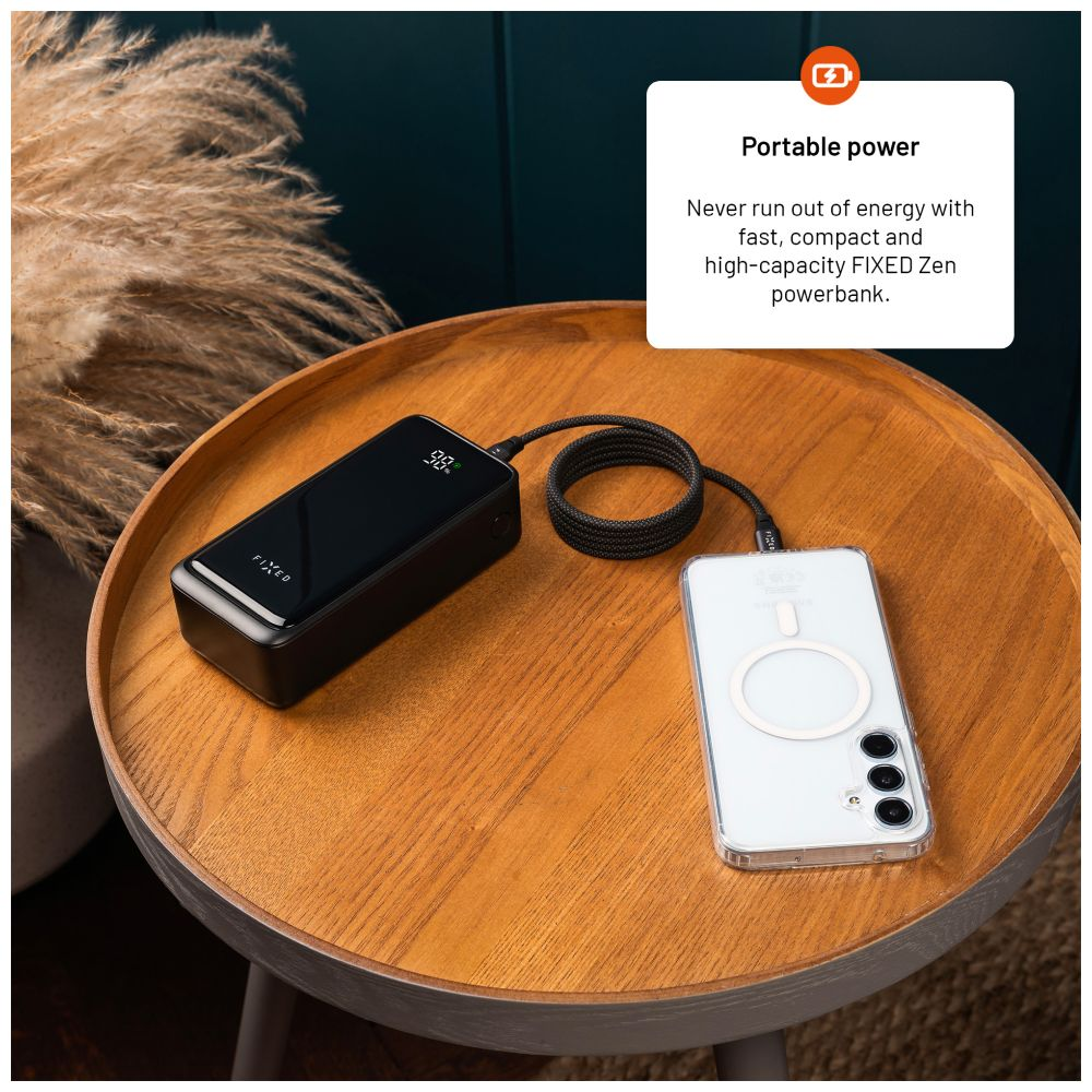Schwarze Powerbank, die ein Telefon auflädt. Die Powerbank zeigt 98 % Ladung an. Das Telefon ist in einer Hülle.