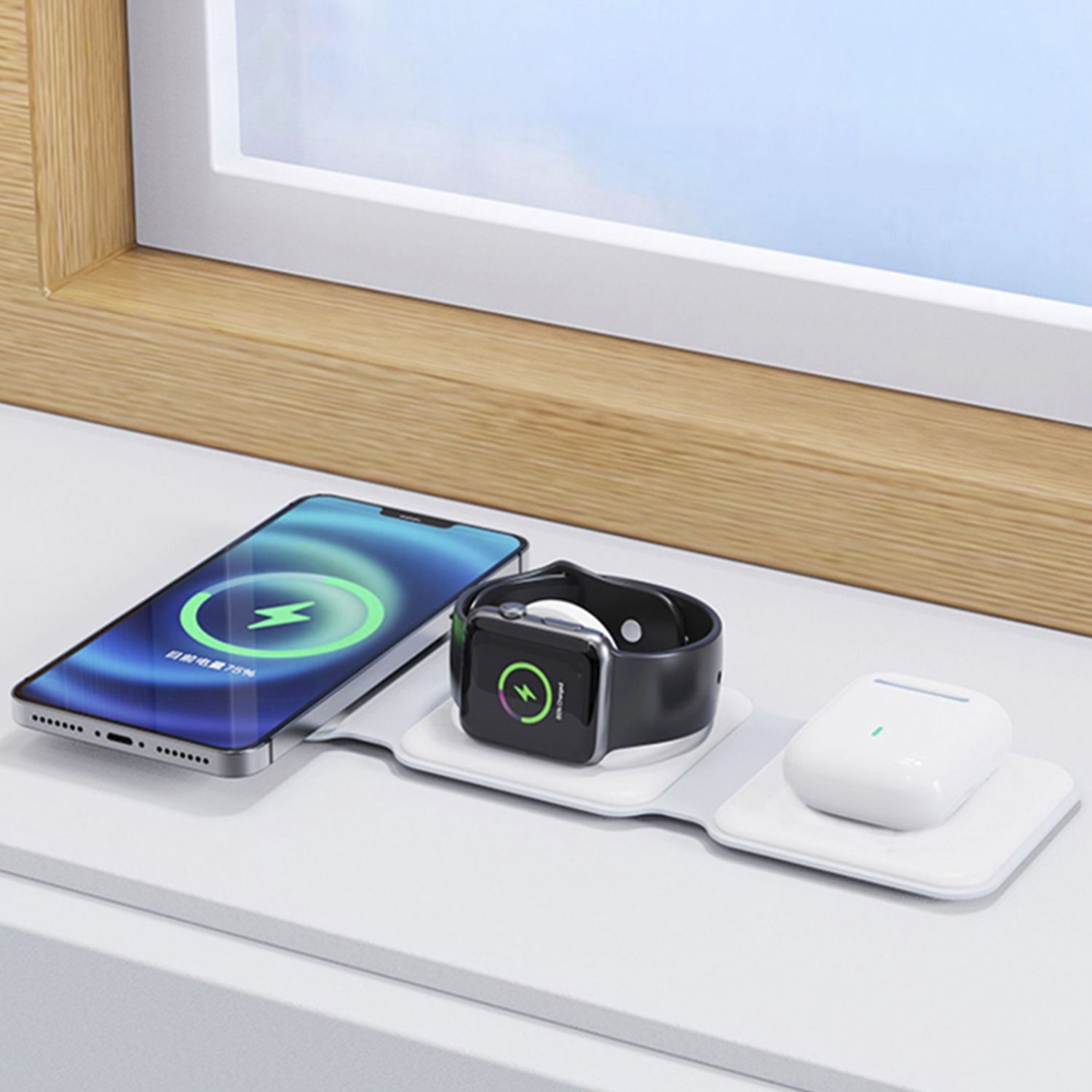 Configurazione di ricarica wireless: telefono, orologio e auricolari su una superficie bianca, vicino a una finestra.