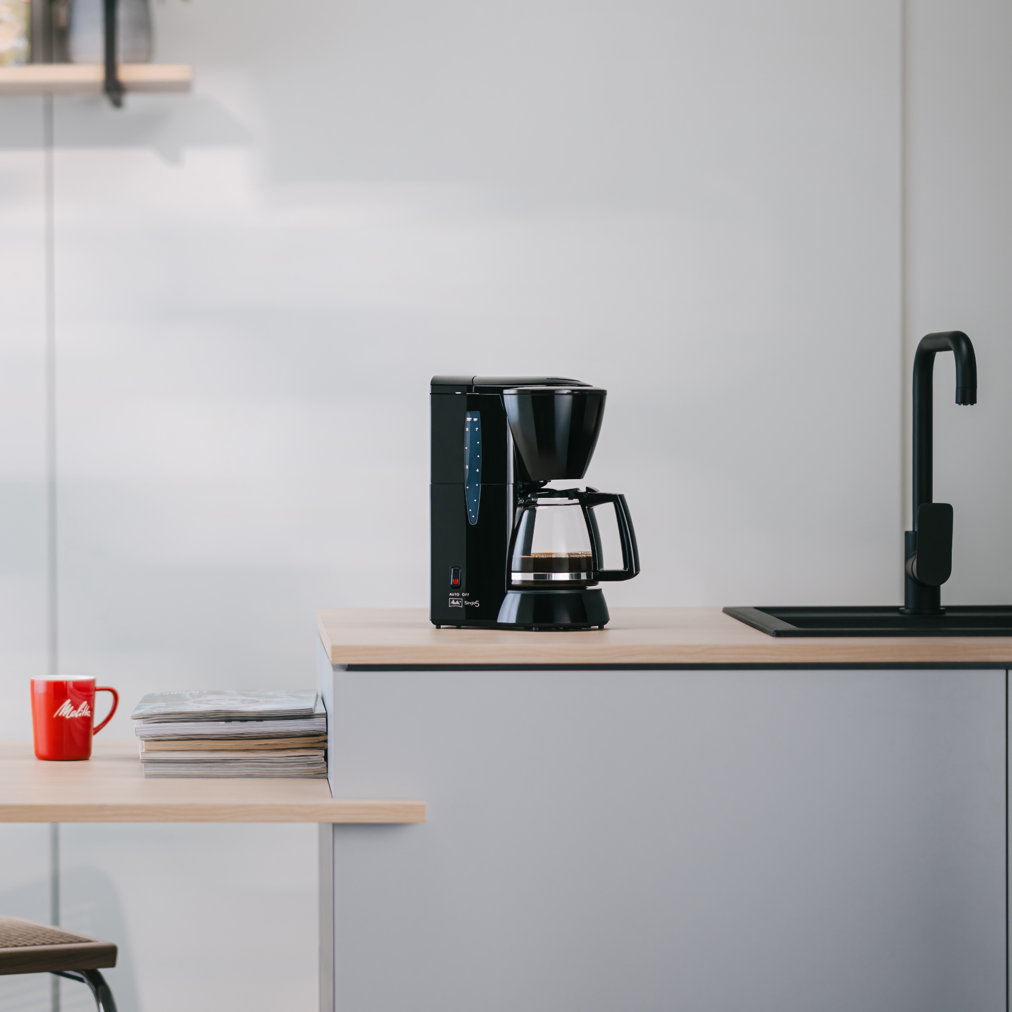 Czarny ekspres do kawy Melitta stoi na blacie w kuchni.