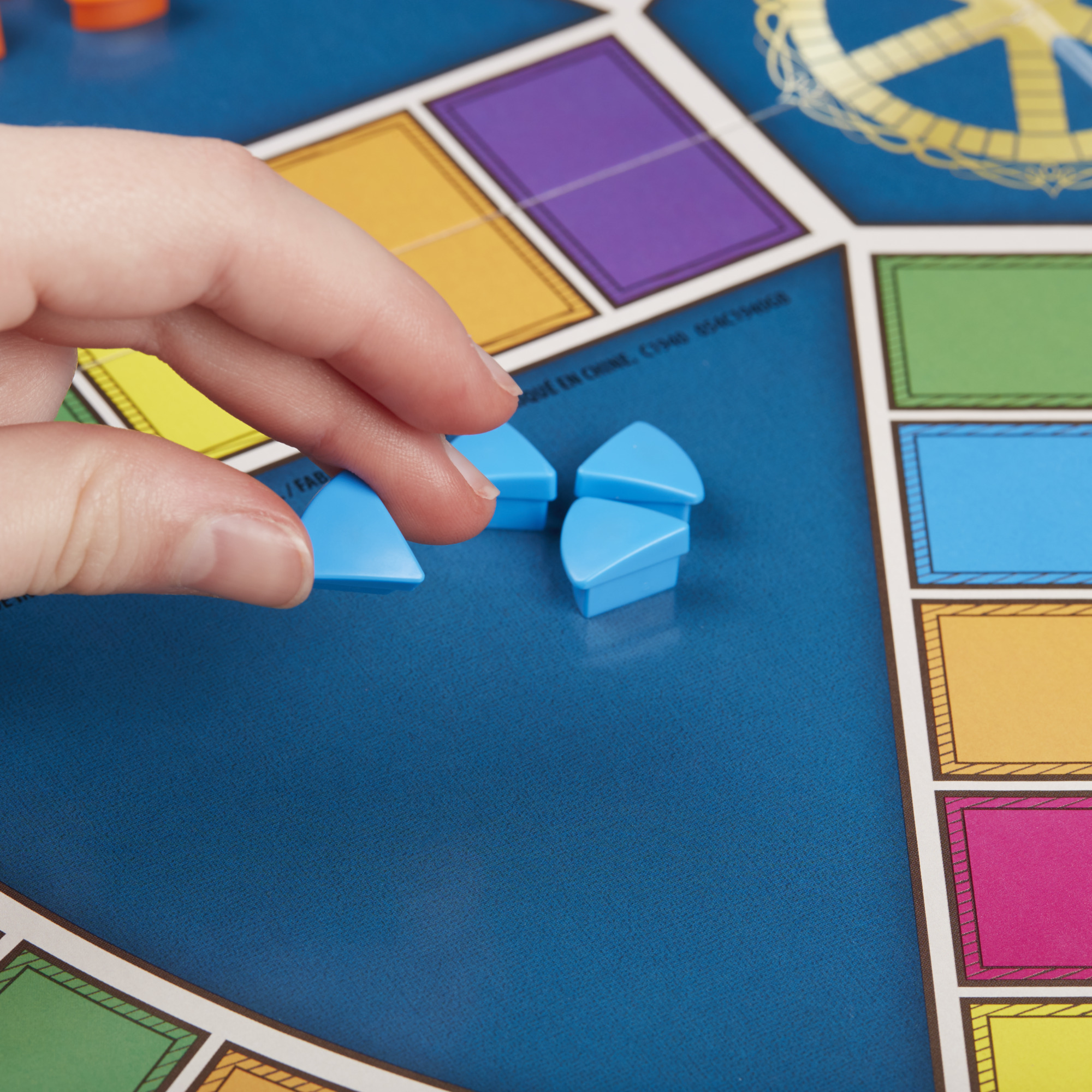 Hand die blauwe spelstukken op een bord vasthoudt. Het bord heeft gekleurde vakken.