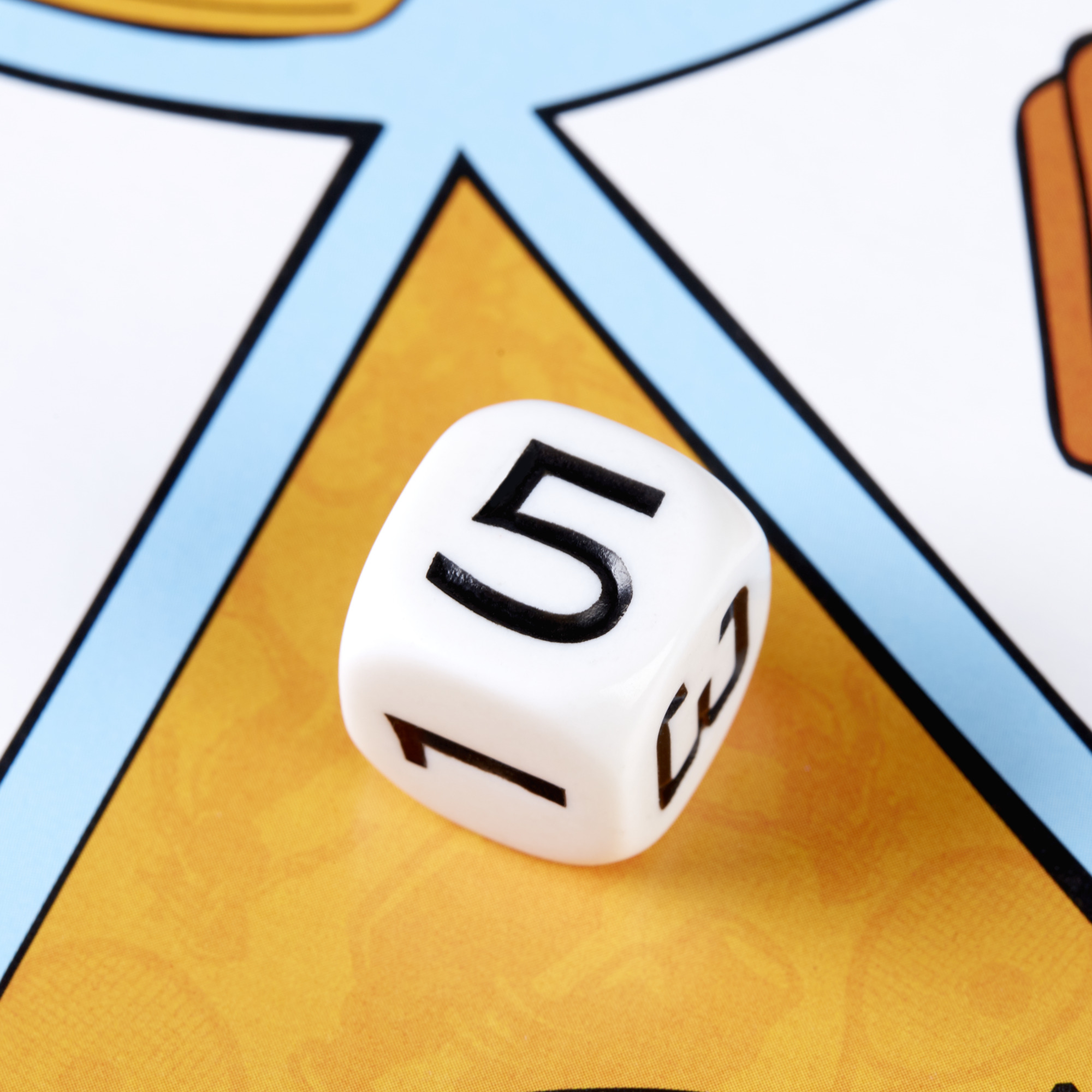 Biała kostka do gry z liczbami. Widoczna liczba 5 i 1. Plansza do gry w tle. Żółte i niebieskie kolory.