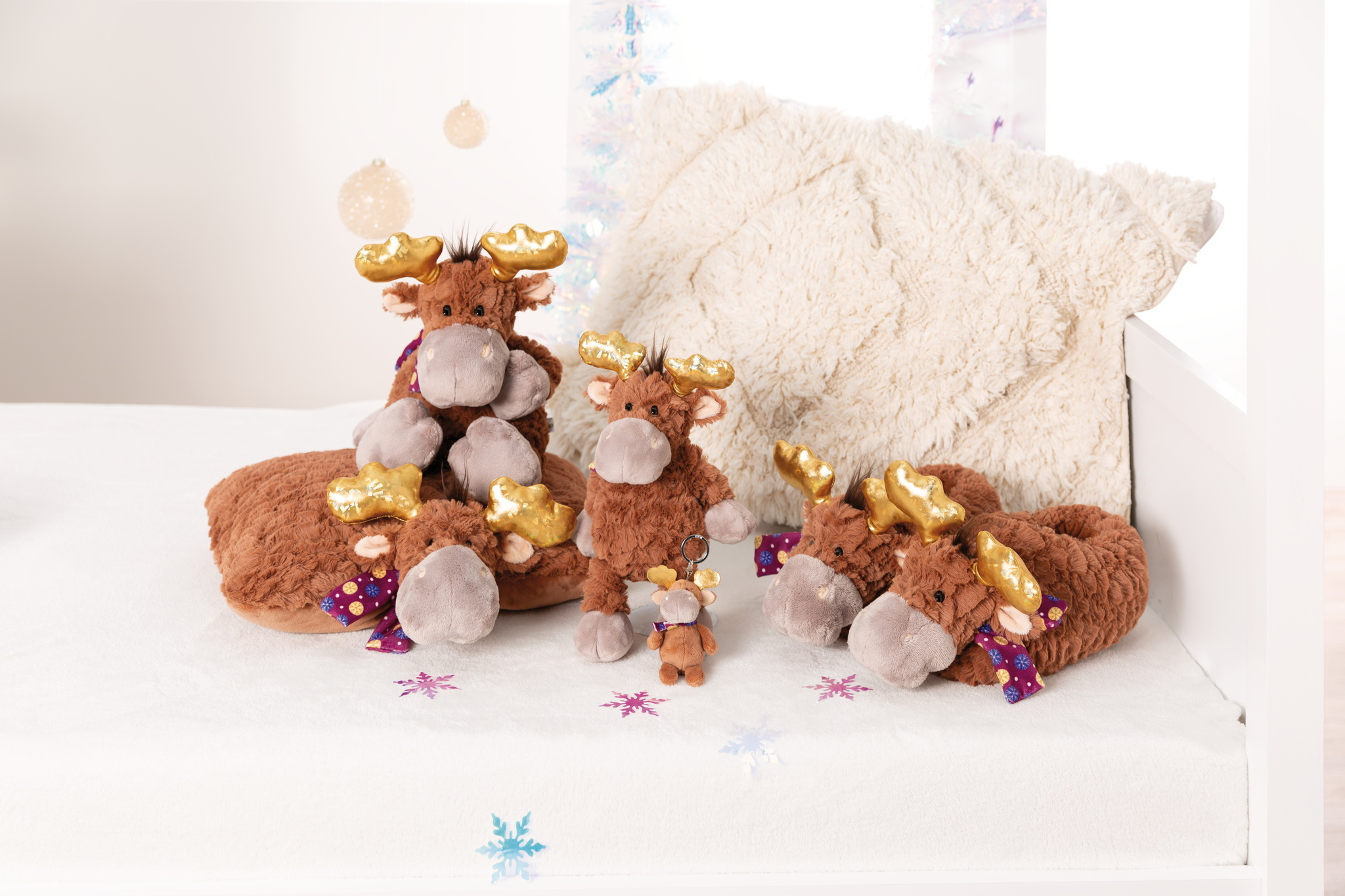 Grupa pluszowych łosi na łóżku z białym tłem.