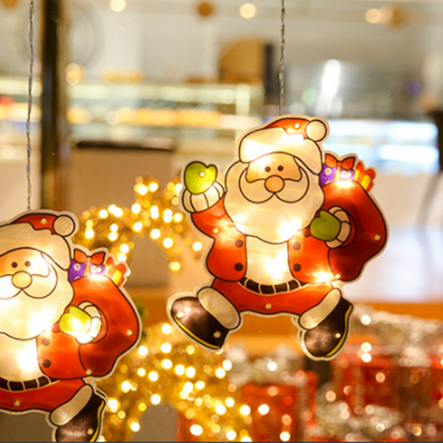 Decorazioni natalizie per finestre con figure di Babbo Natale. Luci e sfondo festoso creano una scena allegra.