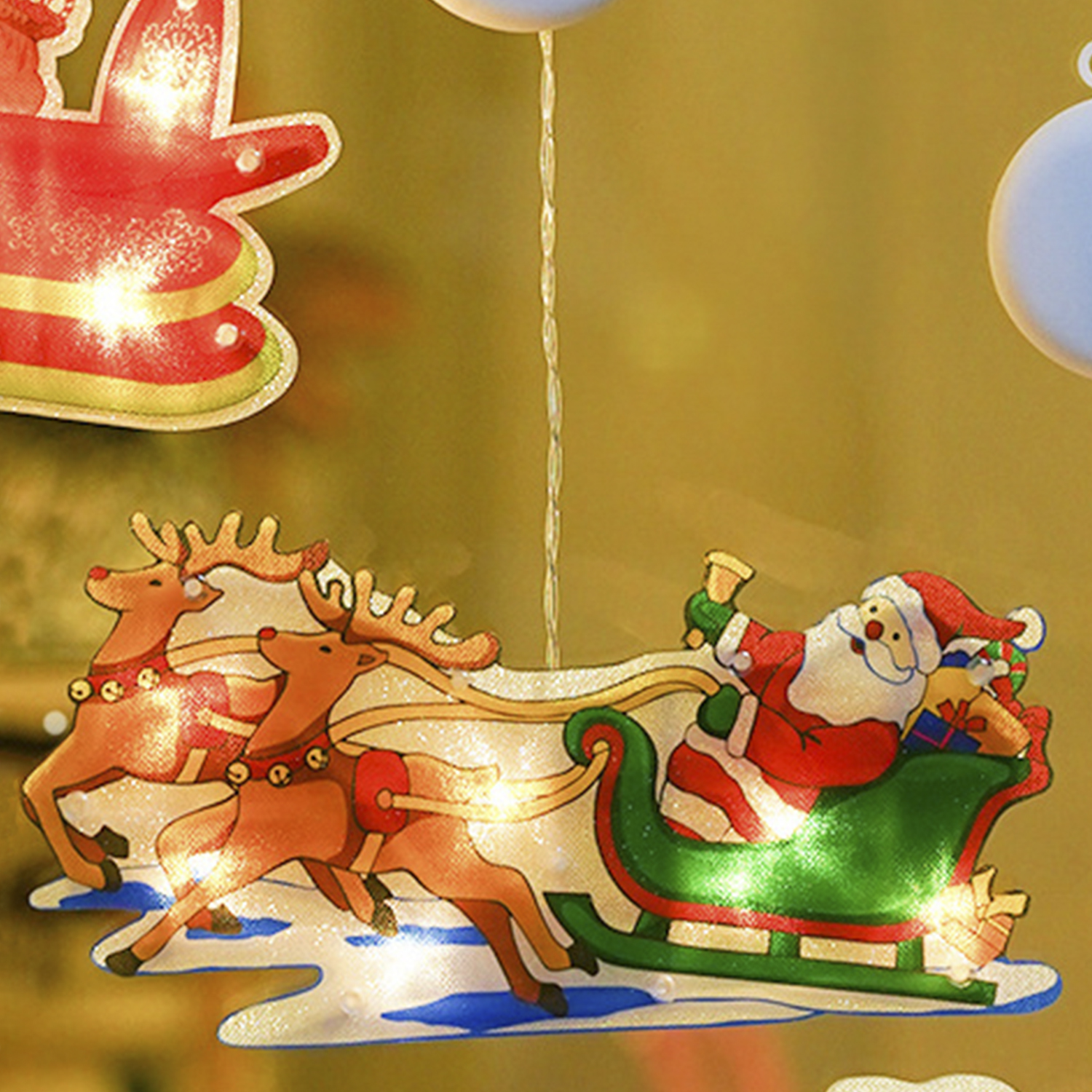 Babbo Natale su una slitta con renne. Luci a tema natalizio intorno alla scena.