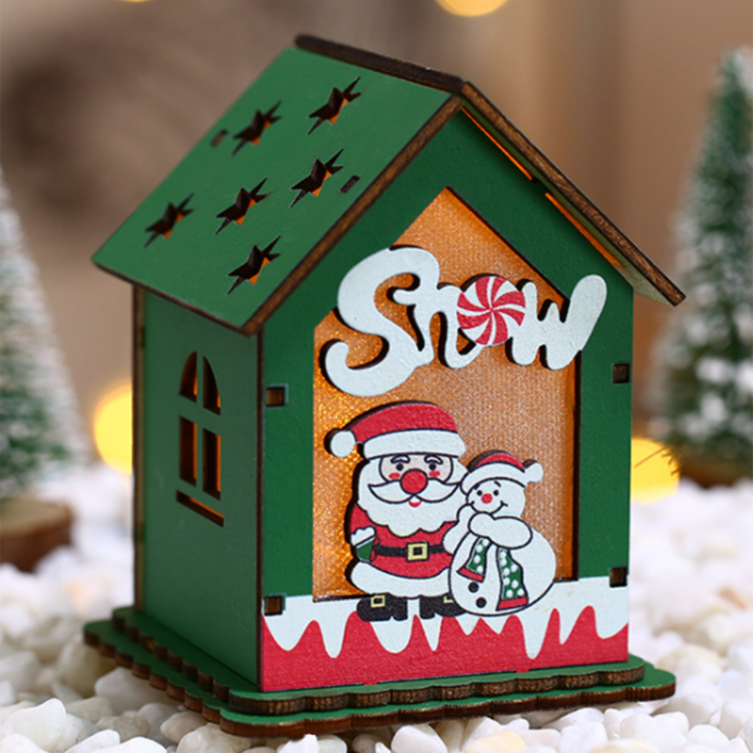 Casa di Natale verde con Babbo Natale e un pupazzo di neve. Cartello di zucchero filato sopra. Base di neve bianca.