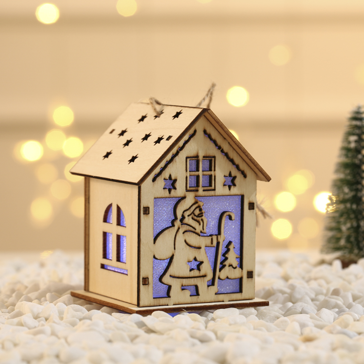 Casa di Natale in legno con ritagli a stella. Sagoma di Babbo Natale nella finestra. Base di neve bianca.
