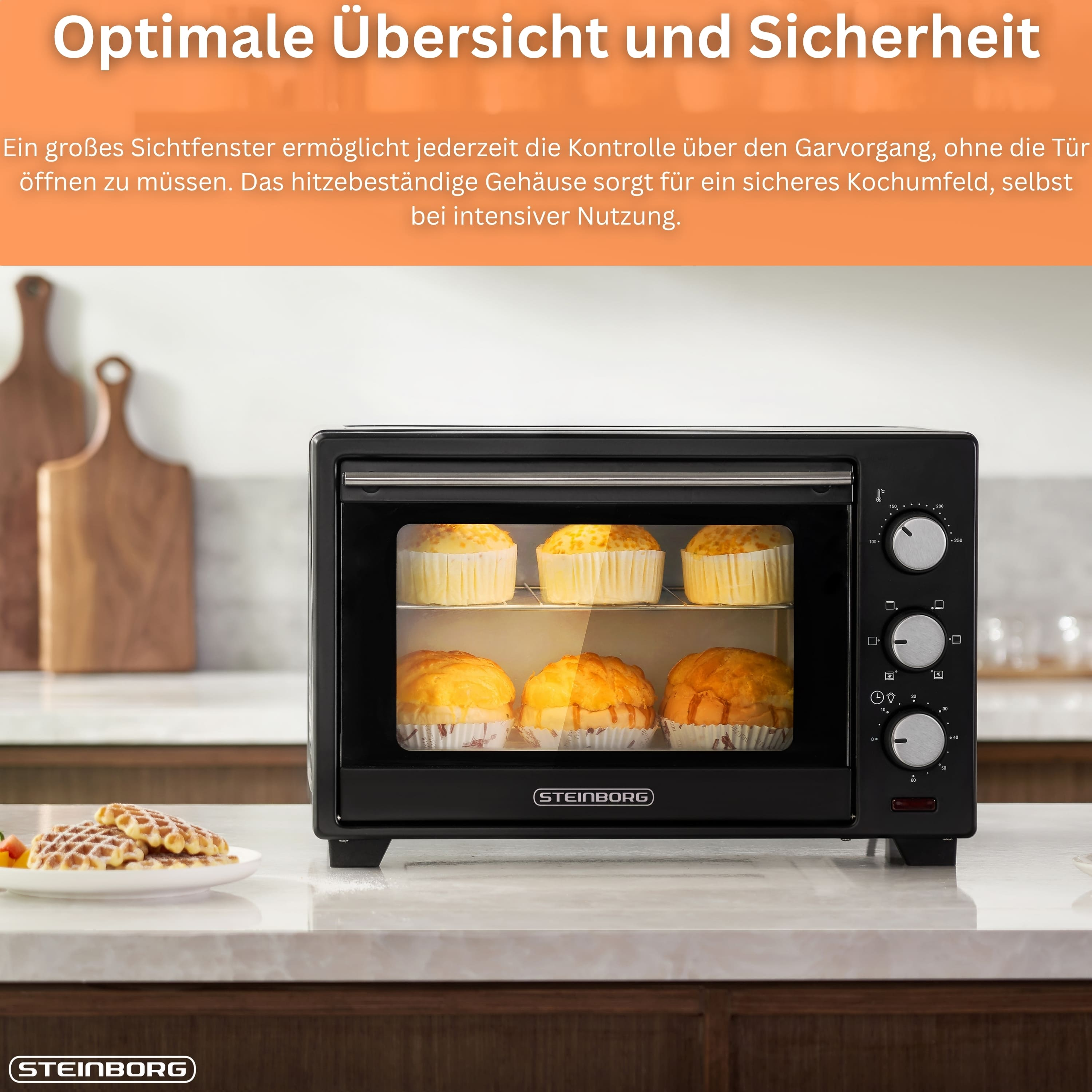 Schwarzer Ofen mit gebackenen Muffins. Bedienelemente rechts. Waffeln und Schneidebretter im Hintergrund.