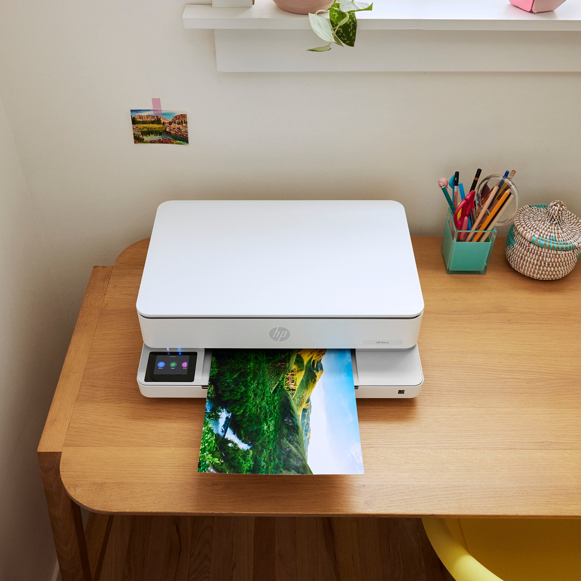 Witte printer die een foto afdrukt, geplaatst op een houten bureau bij een raam.