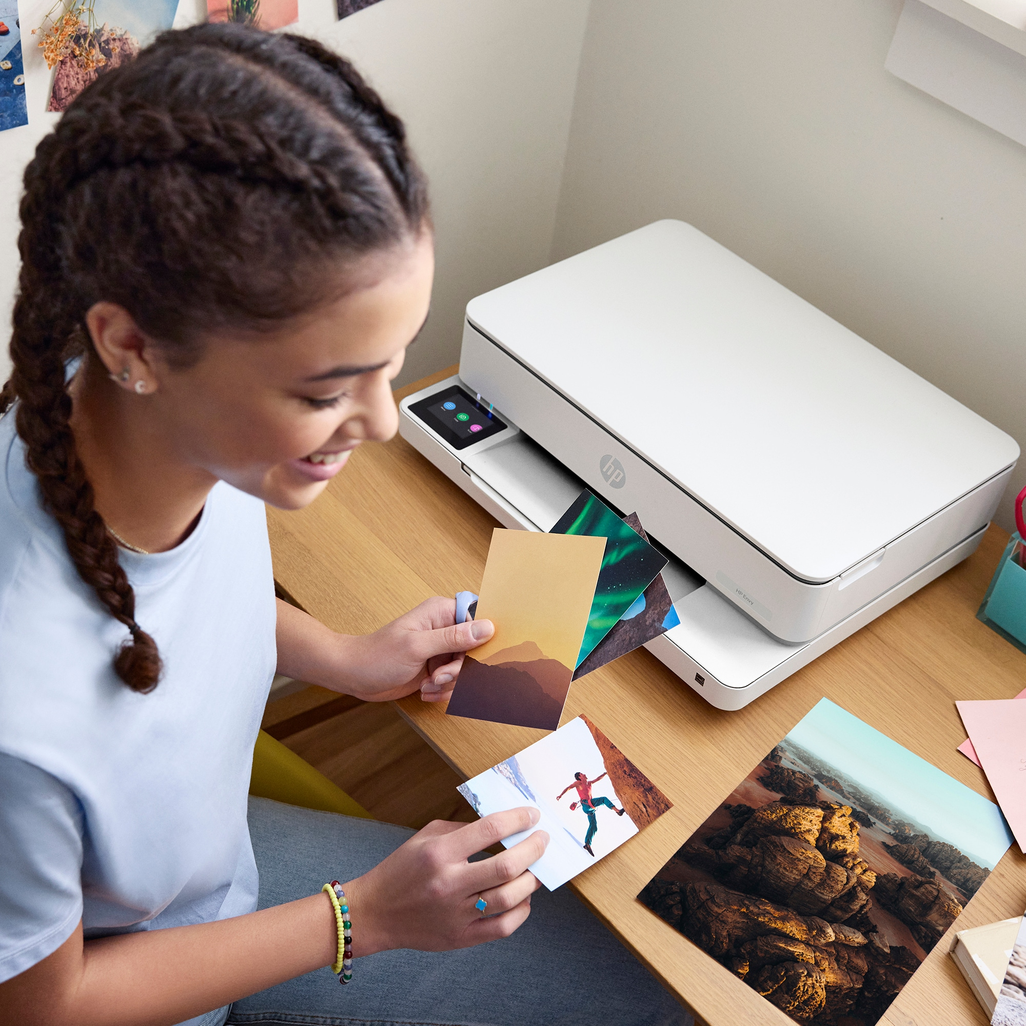 Een jonge vrouw lacht en bekijkt foto's die ze vasthoudt bij een witte HP printer.