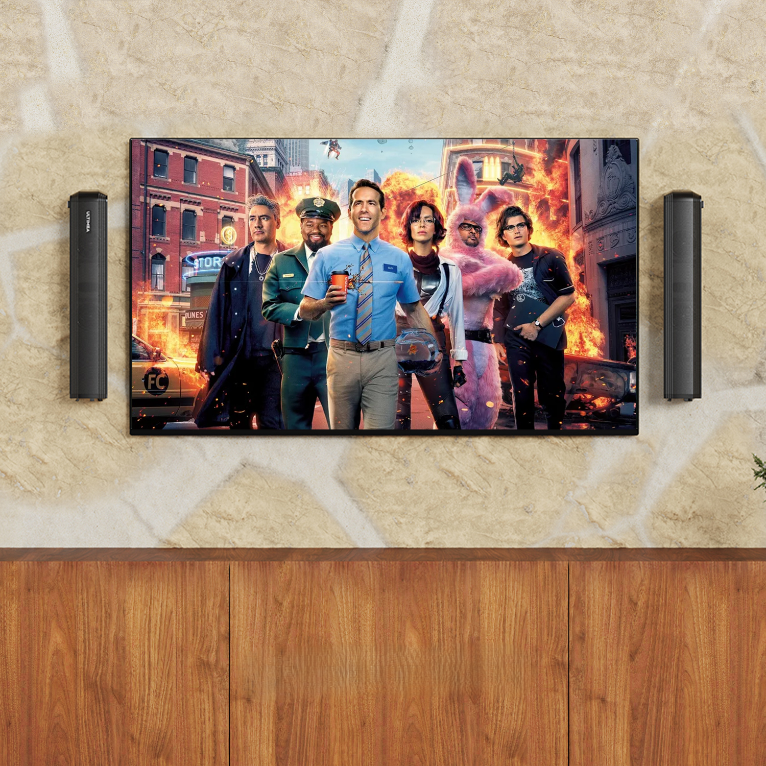 Scena filmowa z aktorami, ekranem i głośnikami. Scena rozgrywa się w pokoju z drewnianą szafką.