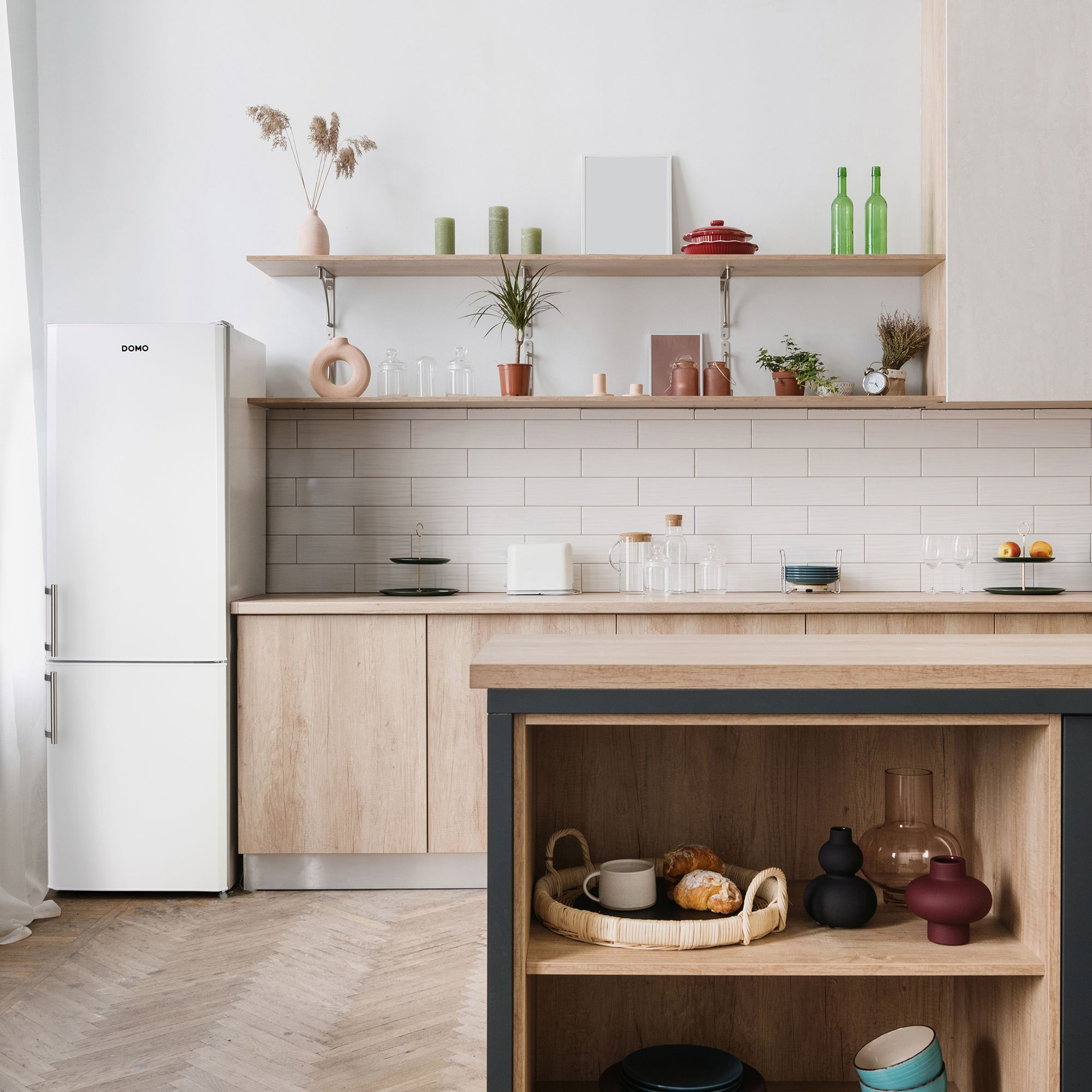 Küche mit weißem Kühlschrank, Holzschränken, Regalen mit Dekoration und einer Holz-Arbeitsplatte mit Gegenständen.
