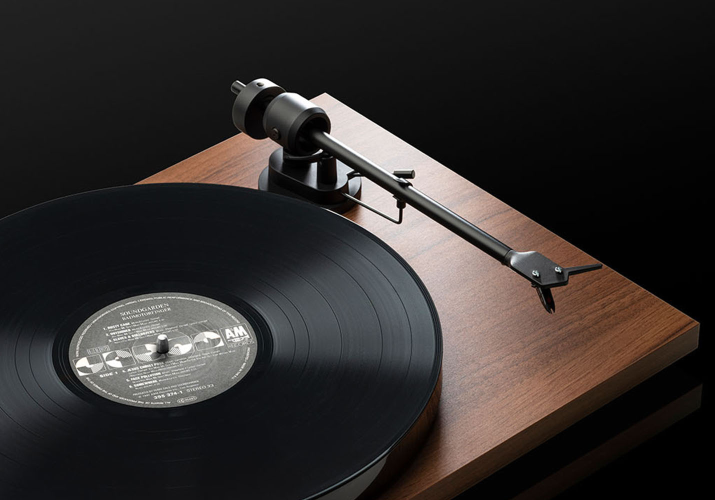 Gramofon odtwarzający płytę winylową, z czarnym ramieniem i ciemną drewnianą podstawą.