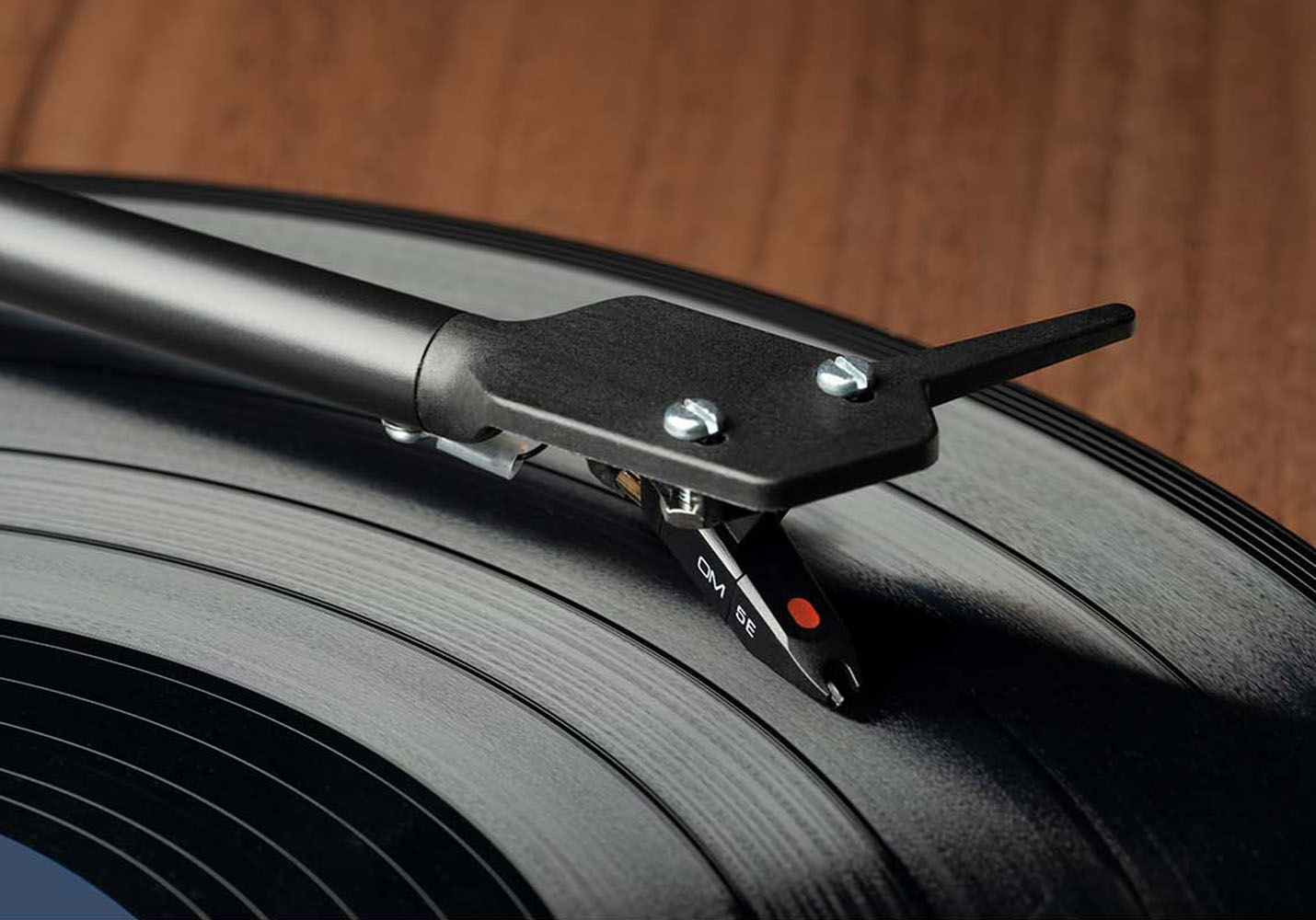 Zbliżenie rysika gramofonu na płycie winylowej. Rysik jest czarny z czerwoną końcówką.