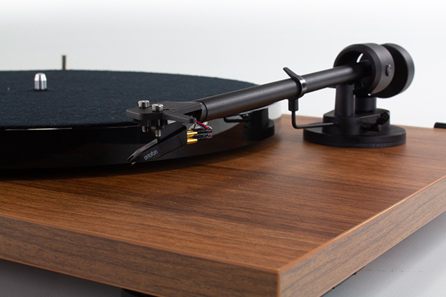 Gramofon z czarną płytą i ramieniem, na drewnianej powierzchni.