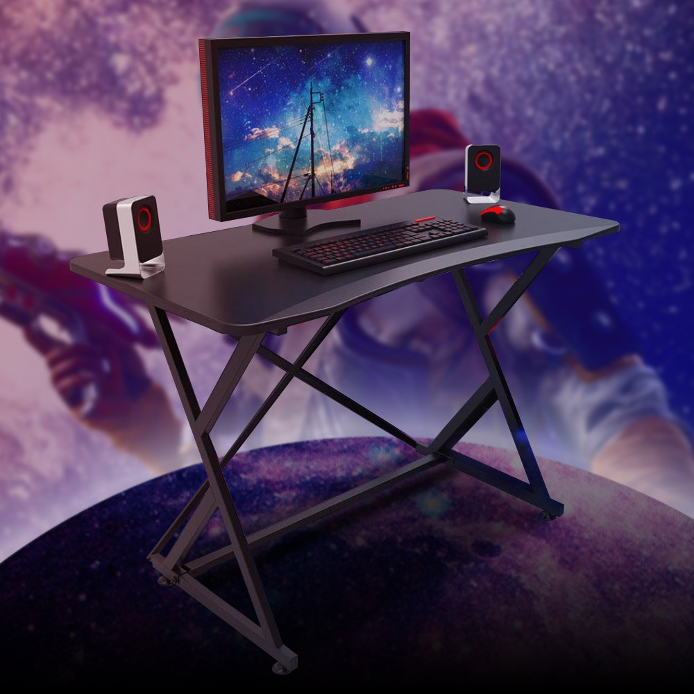 Una scrivania da gioco con monitor, altoparlanti, tastiera e mouse. Lo sfondo è una scena spaziale sfocata.