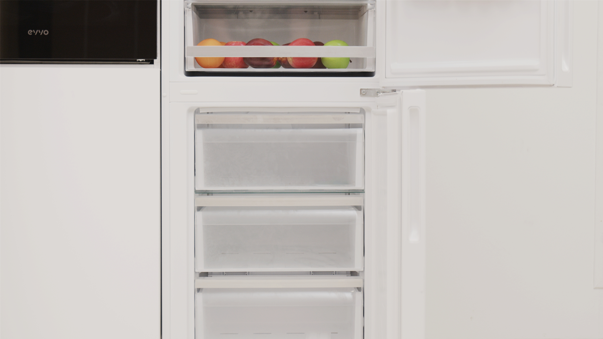 Un refrigerador con cajones de congelador abiertos y una sección superior con fruta.
