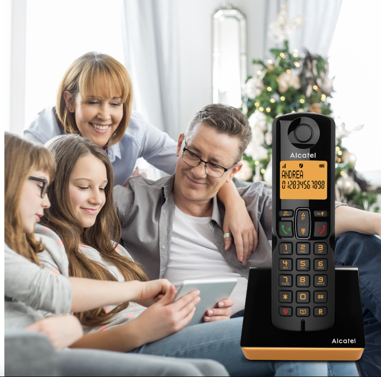Famiglia guarda tablet. Telefono Alcatel in primo piano. Albero di Natale sullo sfondo. Sorrisi.