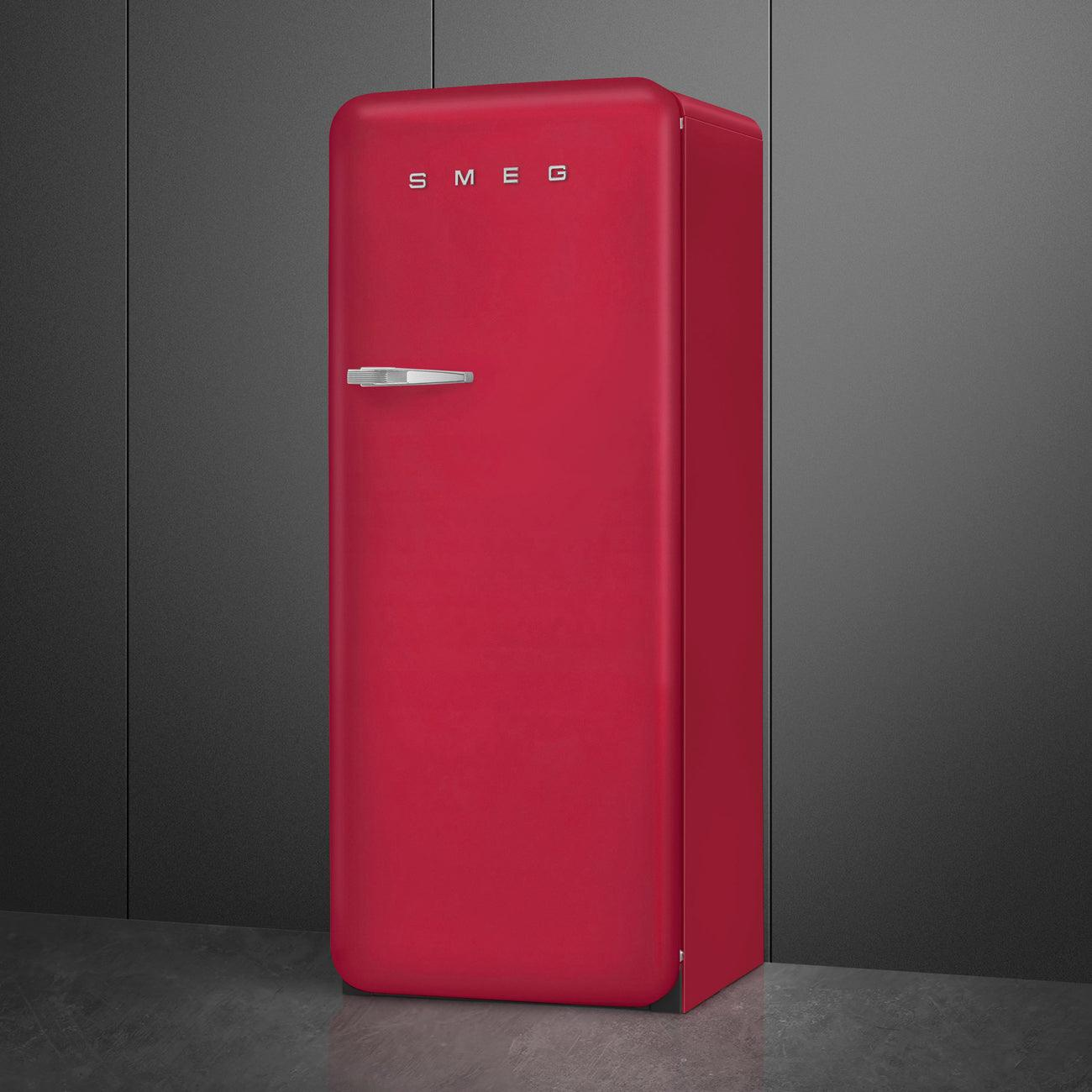 Un frigorifero SMEG rosso con maniglia argentata e logo SMEG su sfondo grigio.