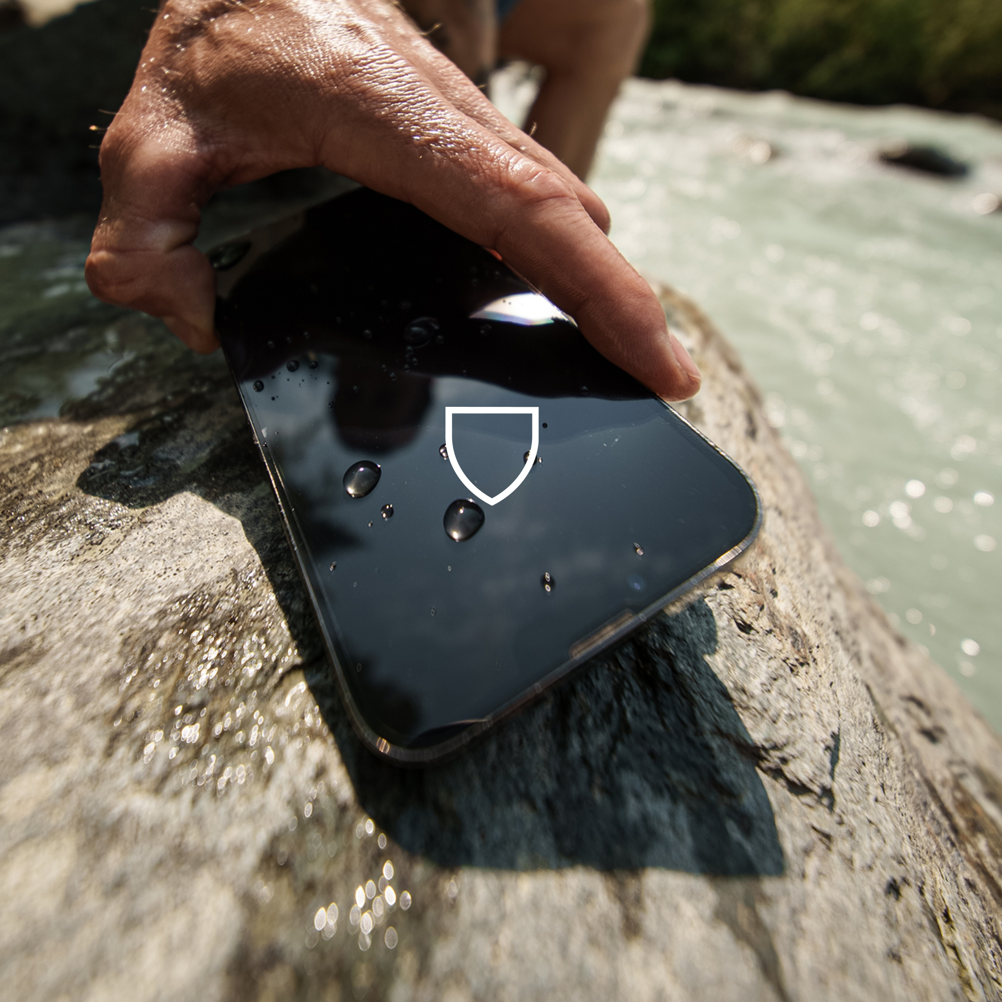 Smartfon na skale z kroplami wody. Ręka trzyma telefon. Ikona tarczy na ekranie.