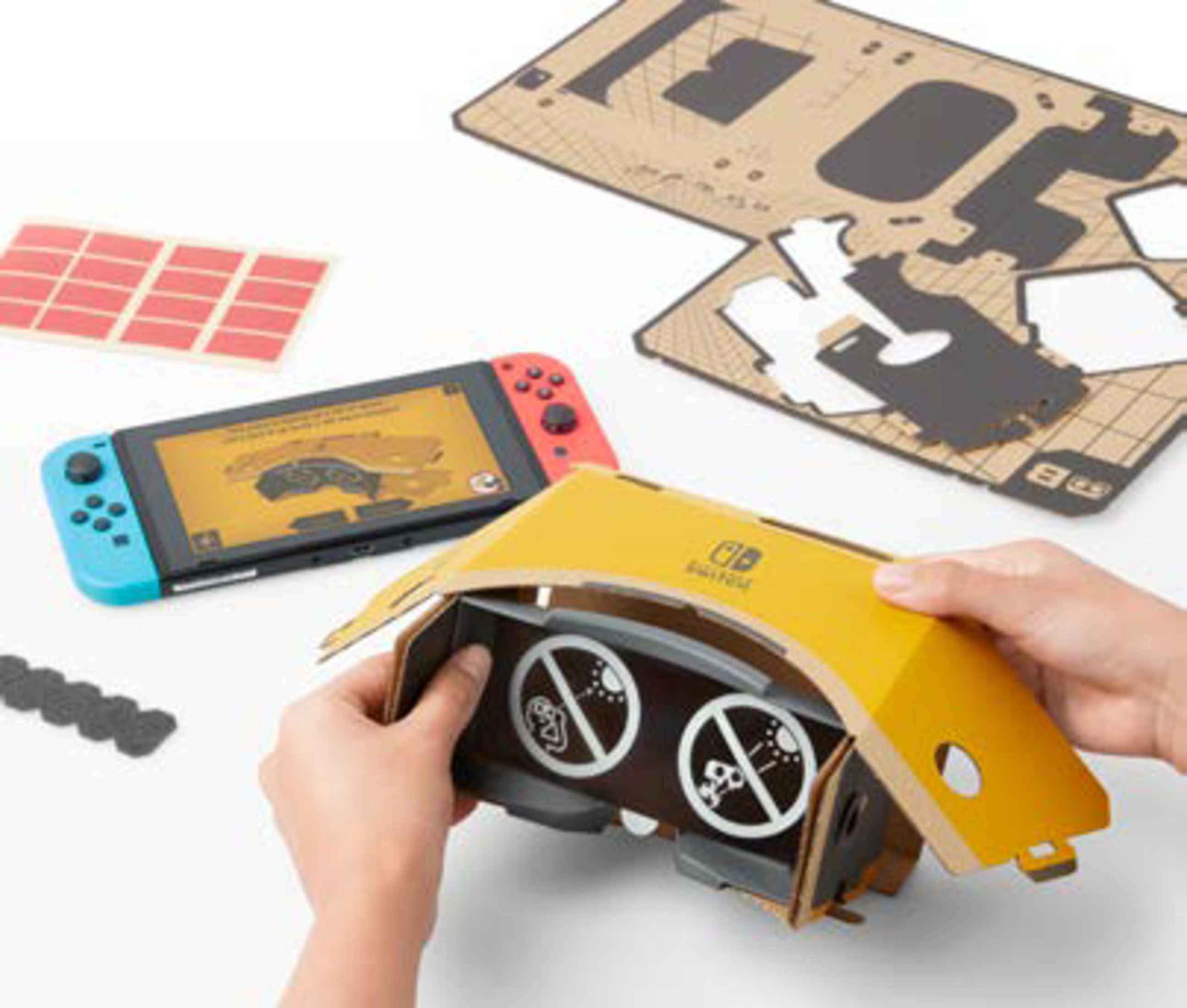 Osoba montuje zestaw słuchawkowy VR i konsolę do gier Nintendo Switch na białym stole.