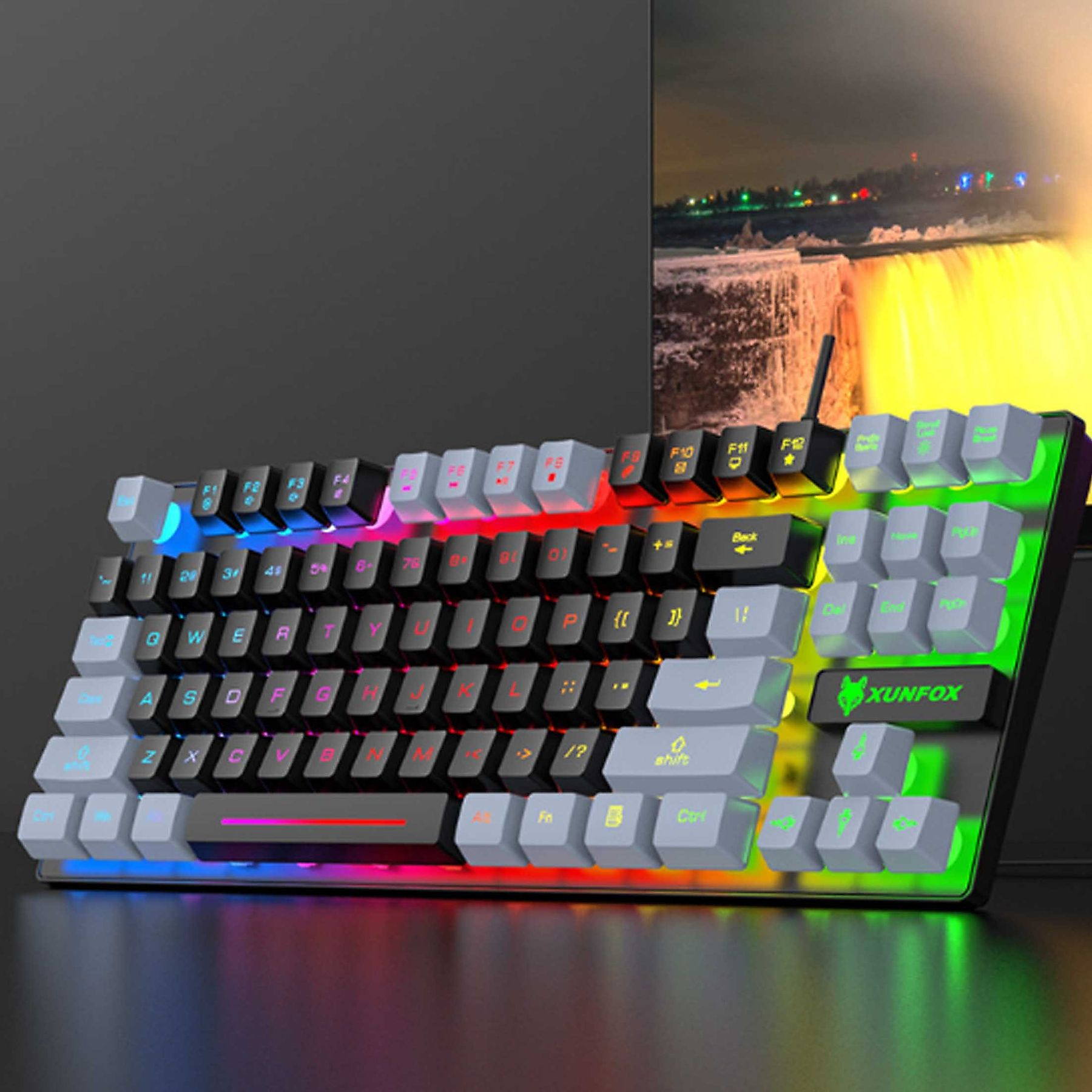 Tastatur mit bunten Lichtern und grauen, schwarzen und weißen Tasten. Die Tastatur steht auf einem Schreibtisch.