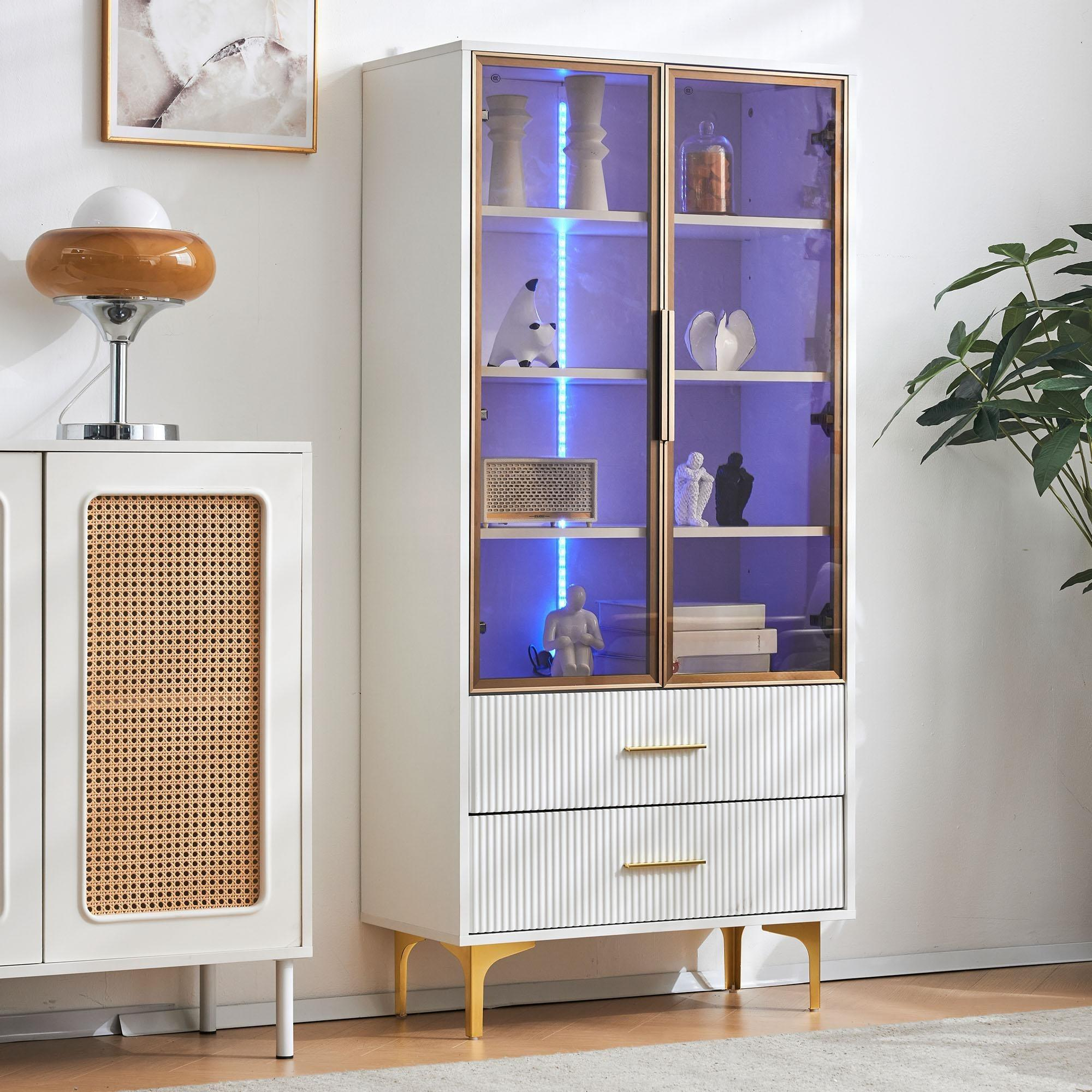 Weißer Schrank mit Glastüren, blauer Innenbeleuchtung und Dekorationsgegenständen. Eine Lampe und eine Pflanze sind gezeigt.
