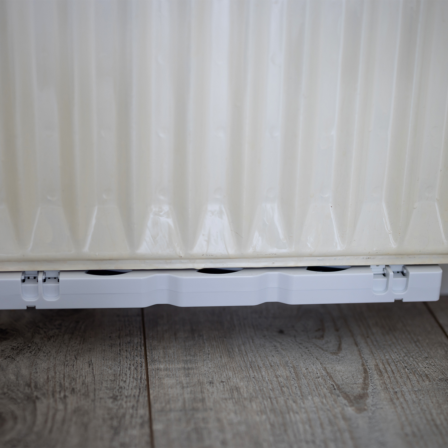 Witte radiator met witte basis op hout.