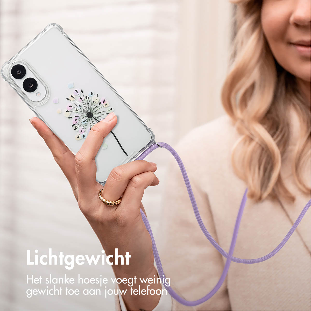 Een hand die een telefoon vasthoudt met een hoesje met paardenbloem design en een koord.