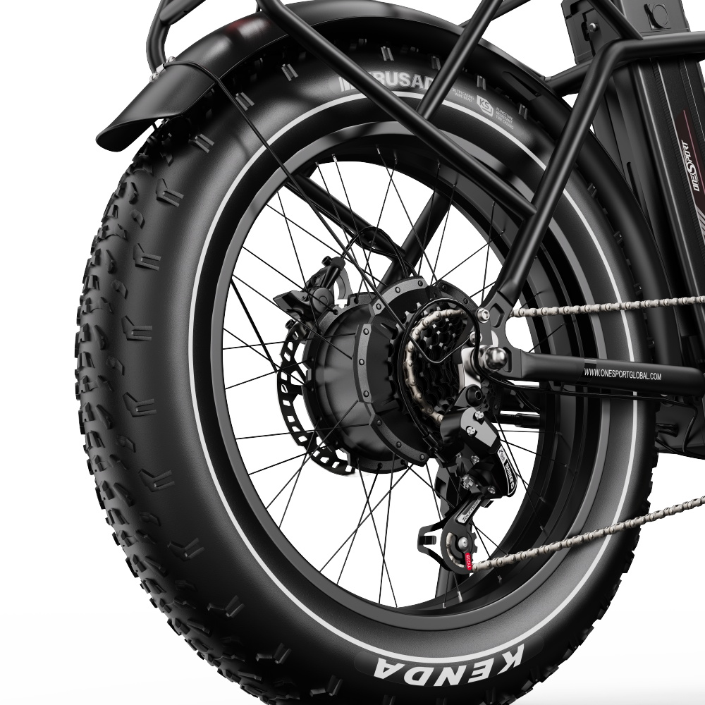 Primo piano della ruota di una bici elettrica nera con pneumatico Kenda. Mostra ingranaggi e freno a disco.