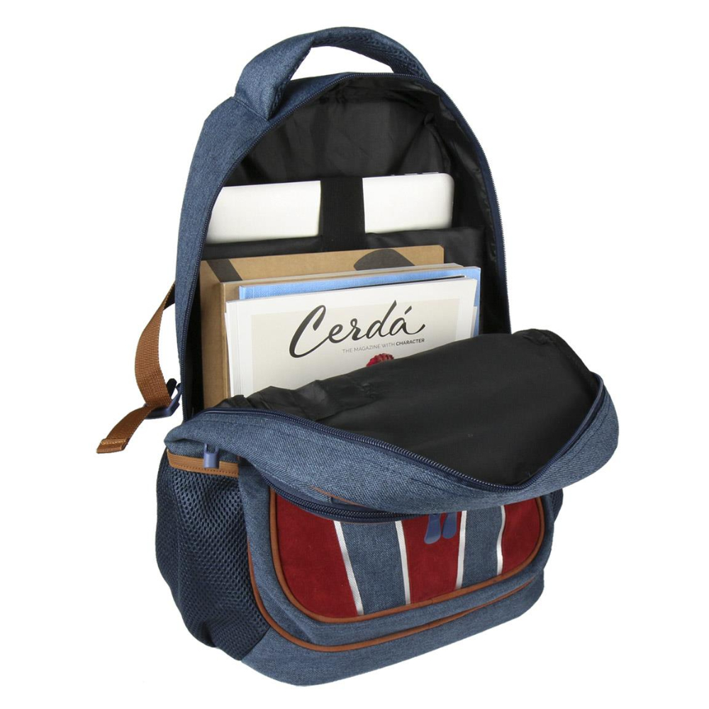 Mochila de mezclilla azul, abierta. Contiene libros y revistas. Bolsillo a rayas rojas y azules al frente. Asa marrón.