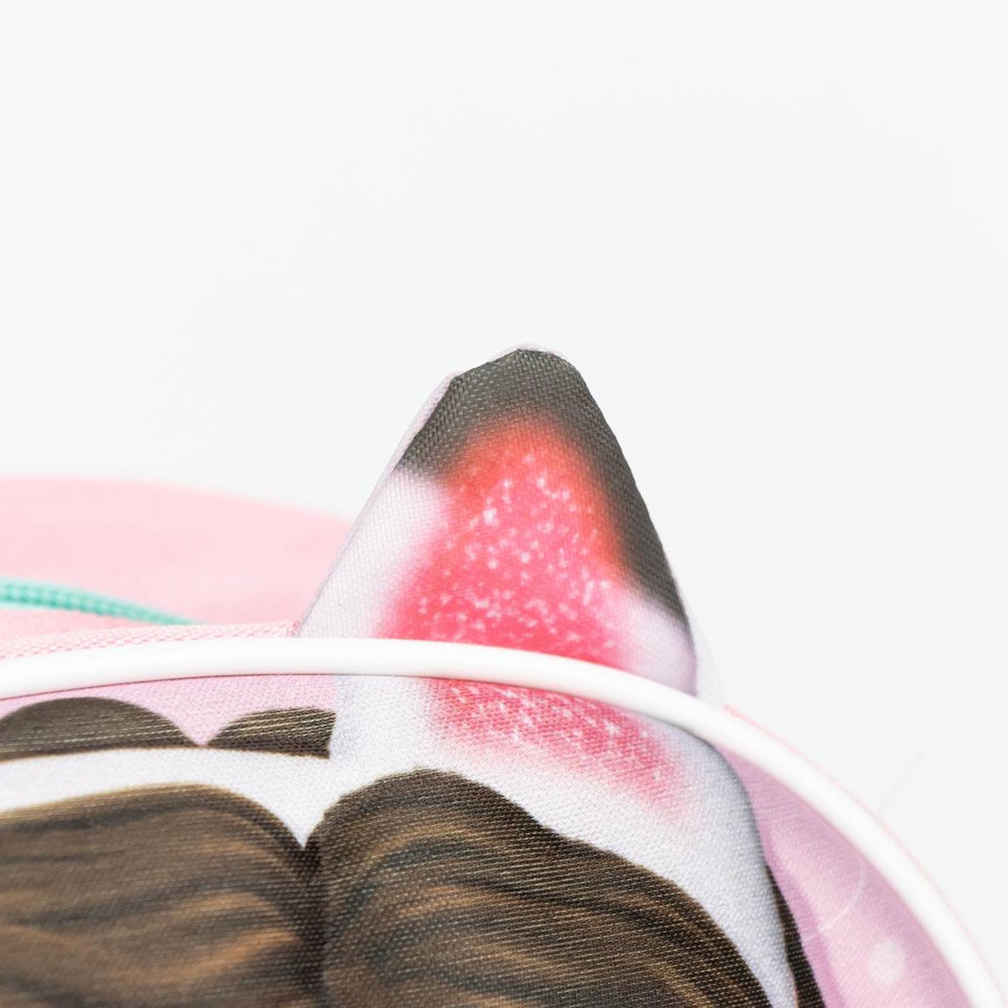 Primer plano de orejas de gato en una mochila rosa. Fondo blanco.
