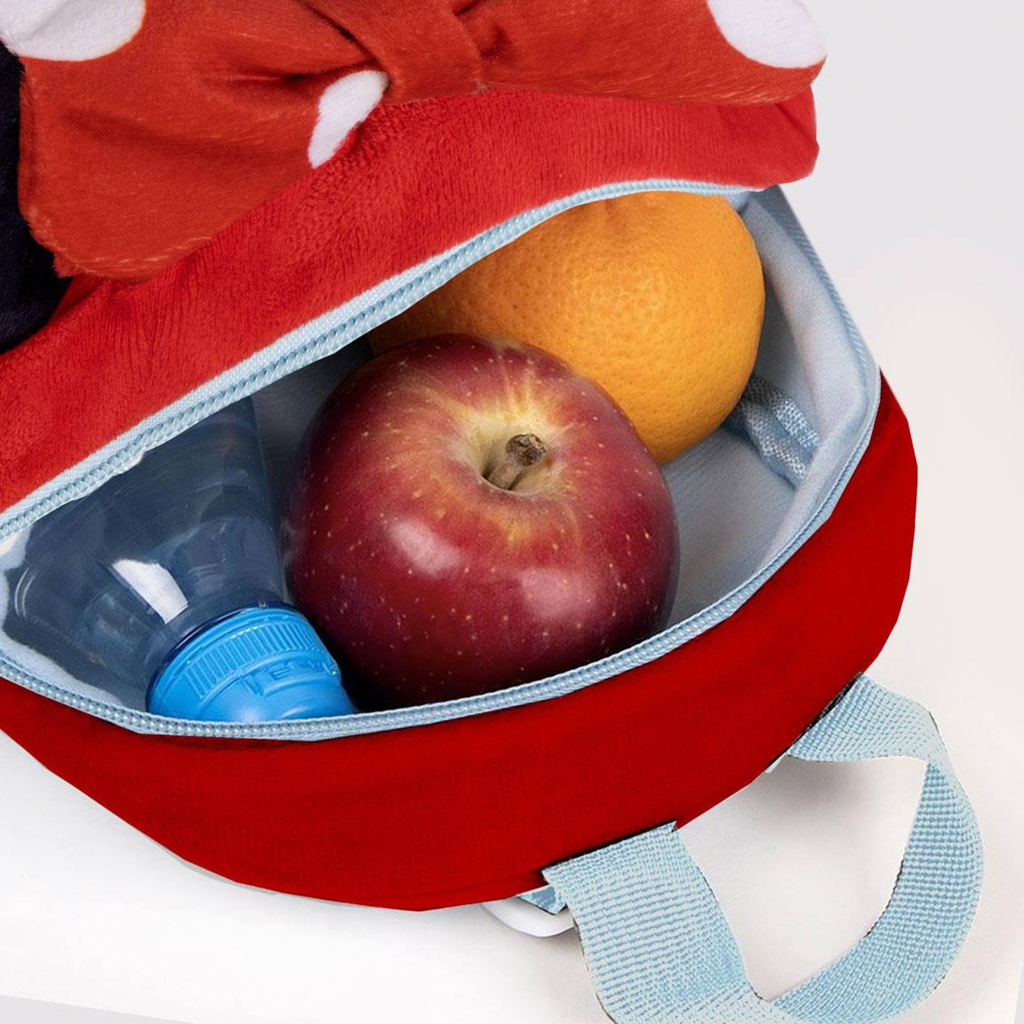 Interior de la mochila de Minnie Mouse. Contiene una manzana, una naranja y una botella de agua.