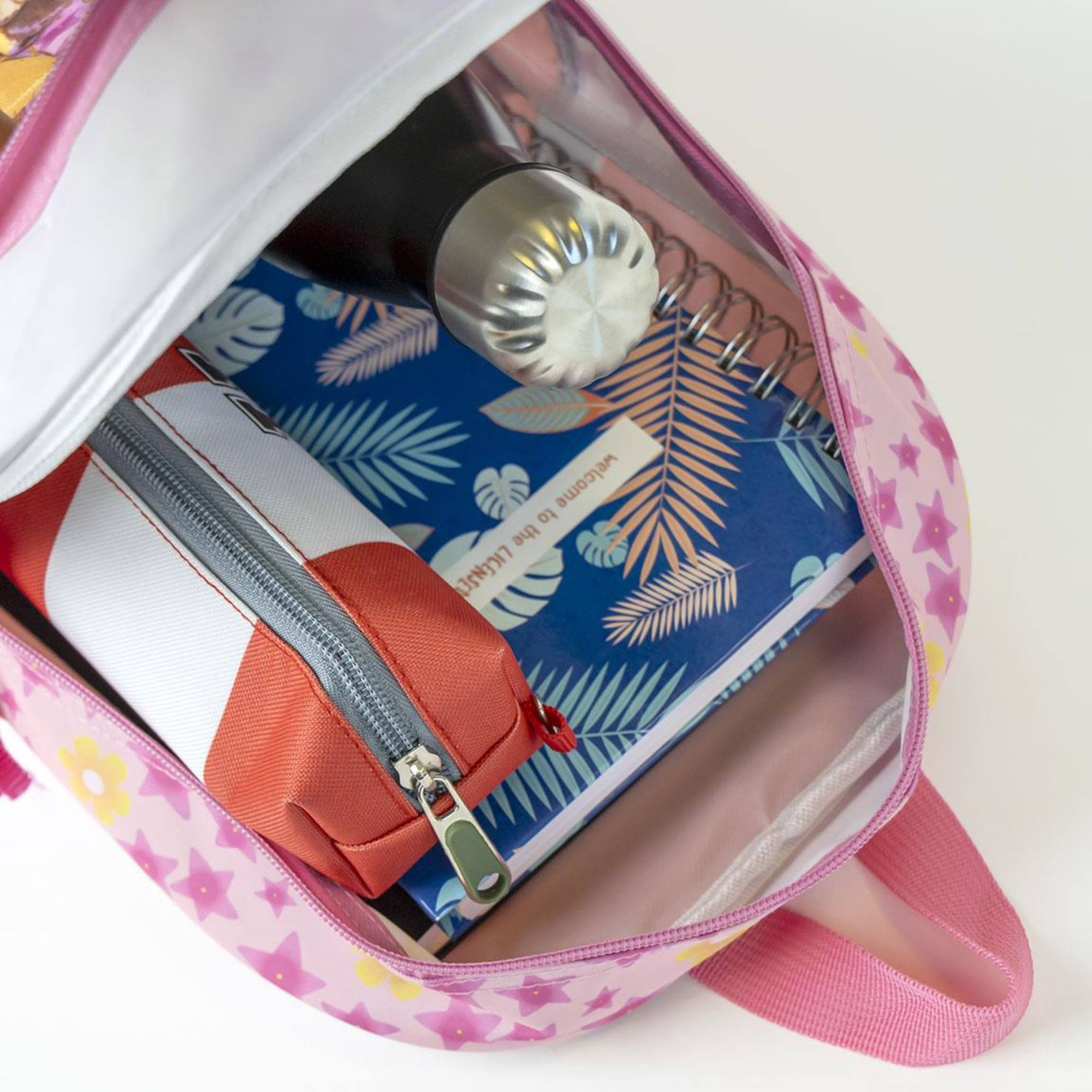 Mochila de unicornio rosa abierta con estuche, cuaderno y botella de agua adentro.