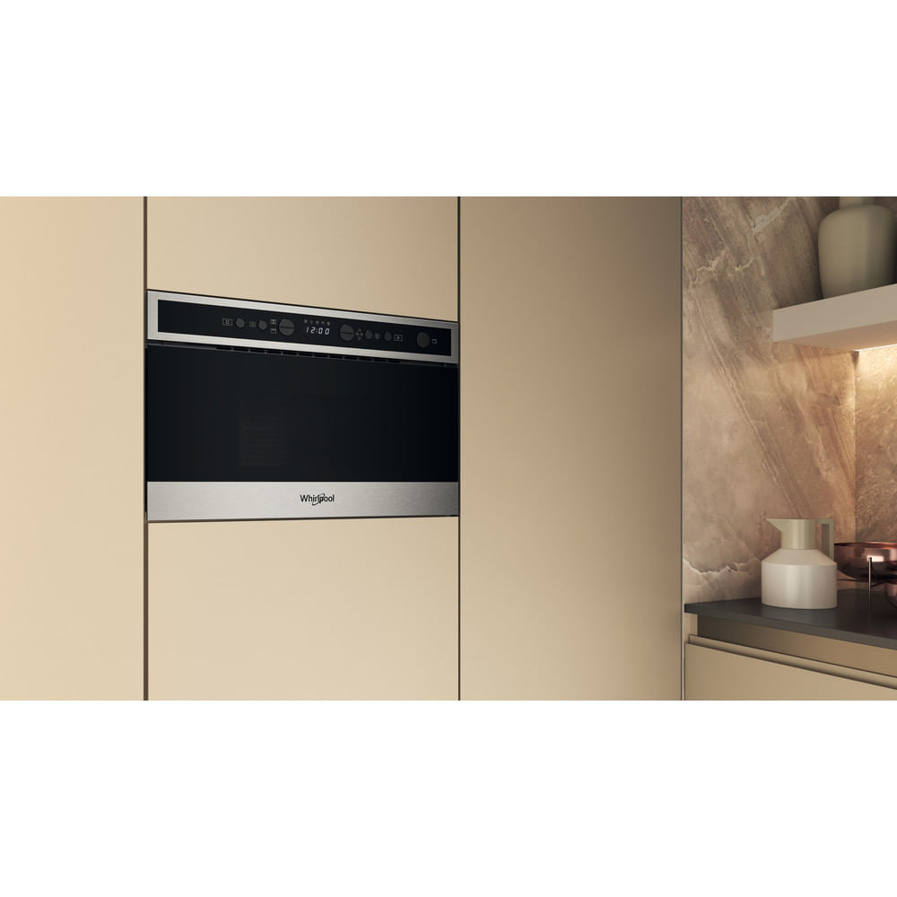 Forno a microonde a incasso in un mobile da cucina beige. Porta nera e finiture in acciaio inox.
