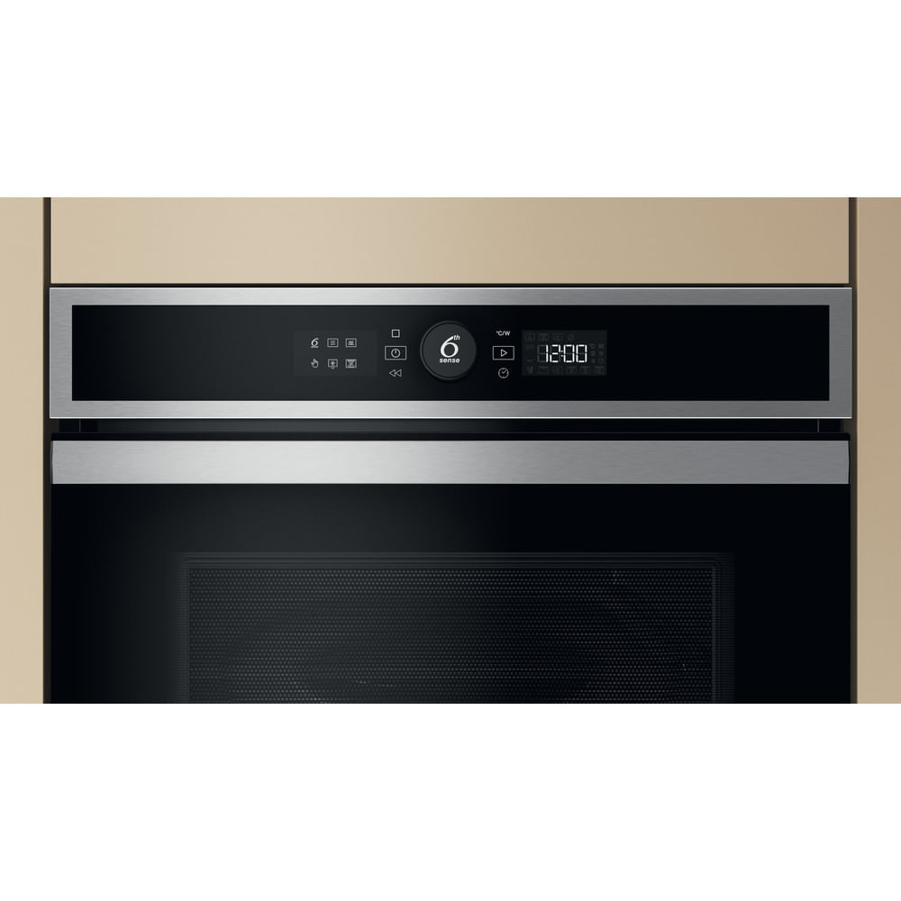 Forno a microonde Whirlpool integrato in una cucina. Il display digitale mostra 12:00. Mobile beige e parete marmorizzata.