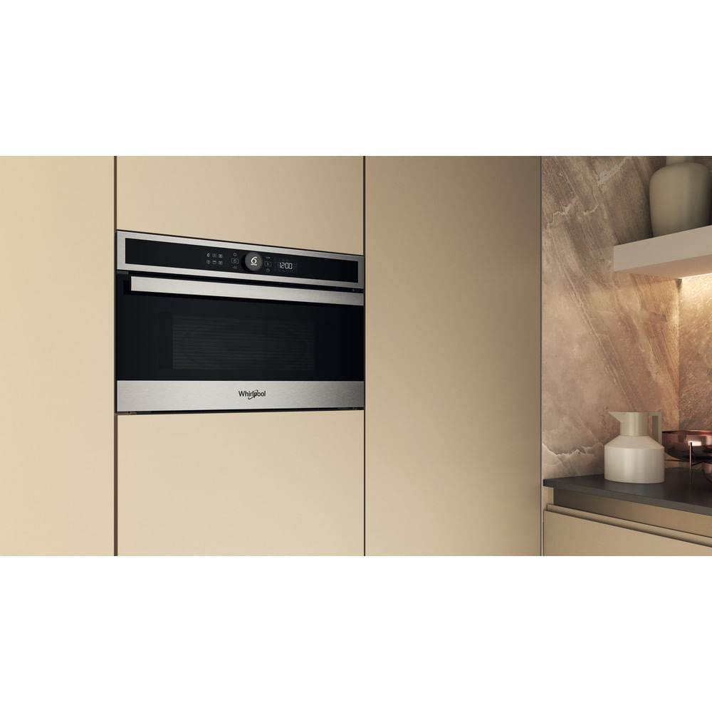 Microondas Whirlpool empotrado en un armario de cocina. Pantalla digital muestra 12:00. Armario beige.