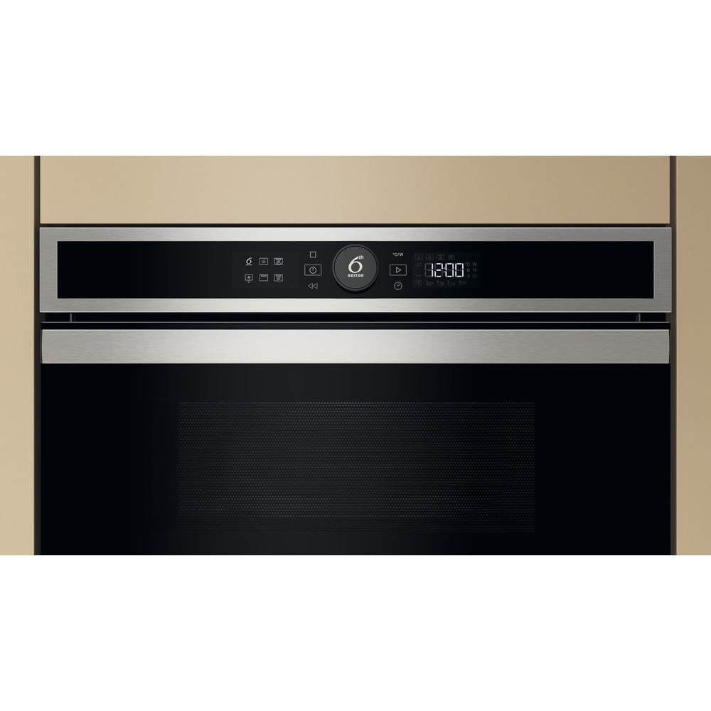 Microondas Whirlpool empotrado en un armario de cocina. Pantalla digital muestra 12:00. Armario beige.